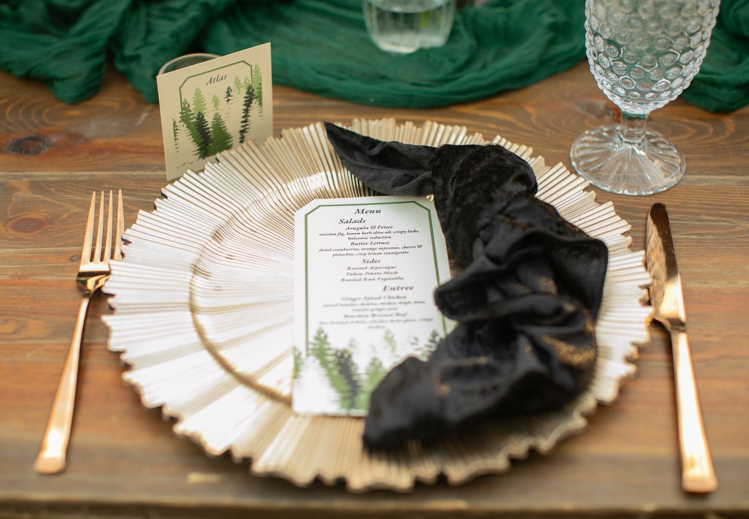 Elegant place setting with gold charger plate, black napkin, and menu card.
