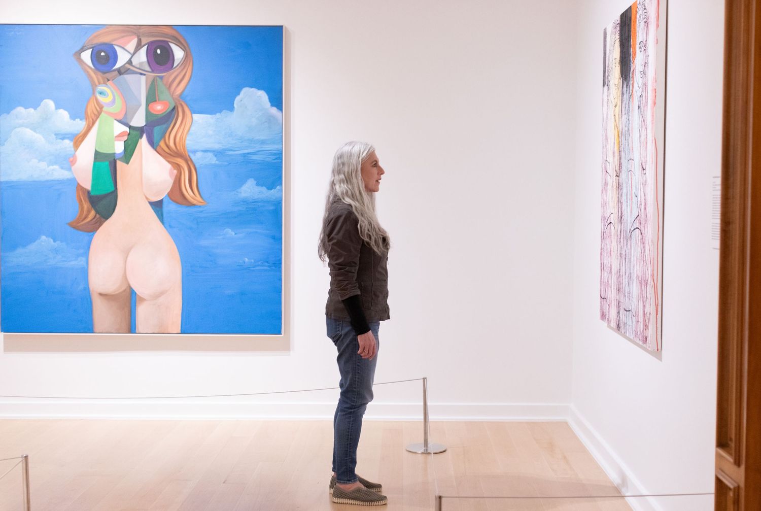 Gallery visitor observing colorful modern artwork in a white-walled museum space.
