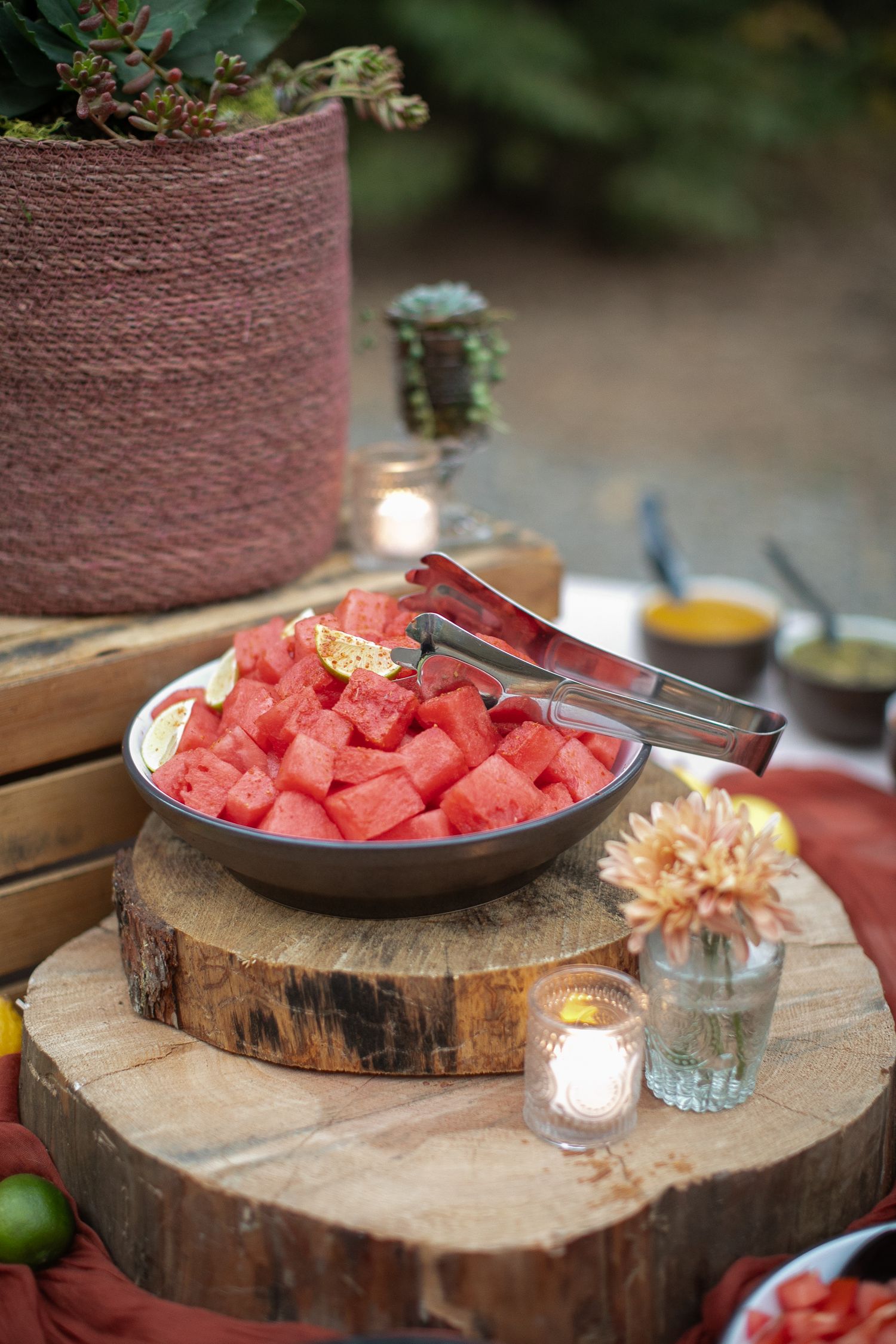 Fresh watermelon cubes served on wooden slices with decorative candles.