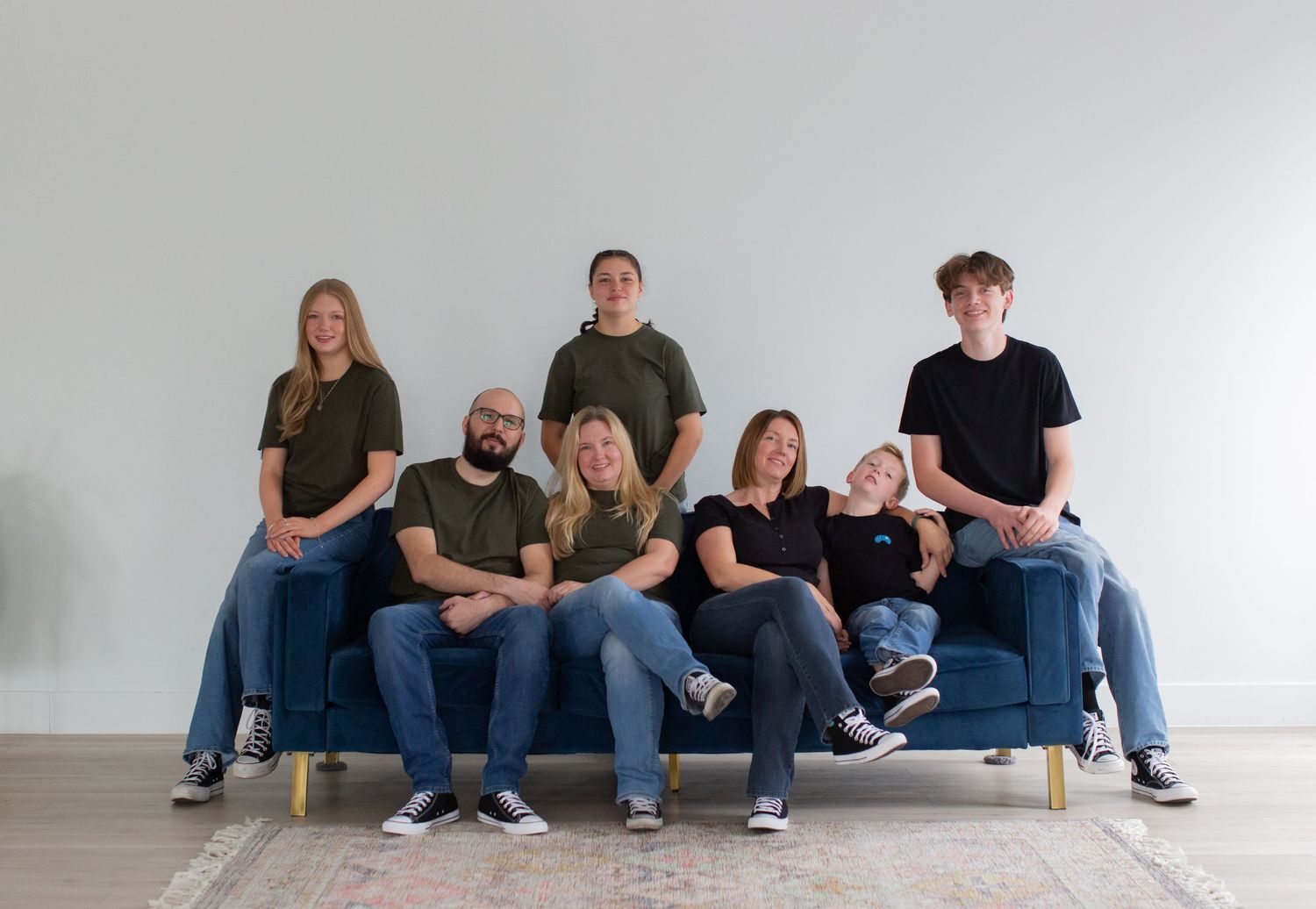 A group casually lounges together on a gray couch in a bright modern room with plants.