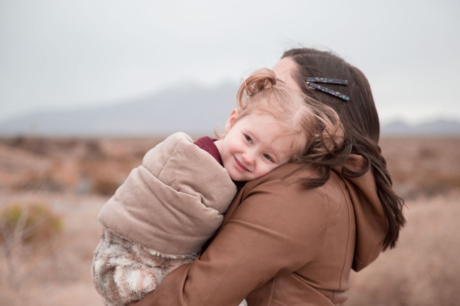 A cozy embrace between mother and child in a desert landscape.