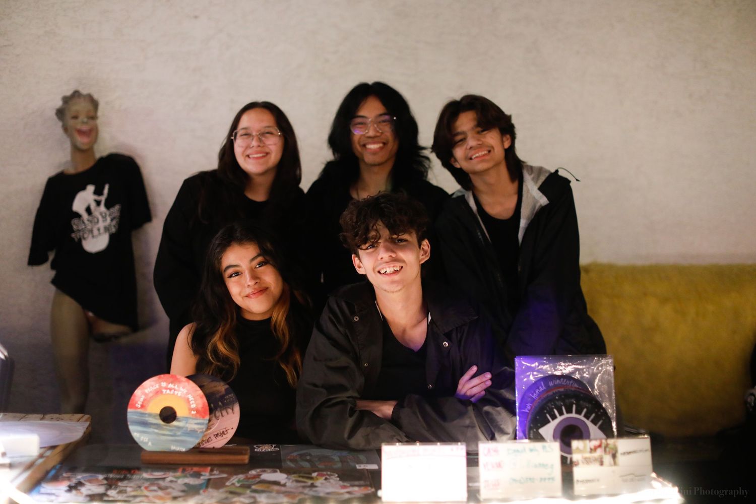 Group gathered together indoors against a light colored wall.