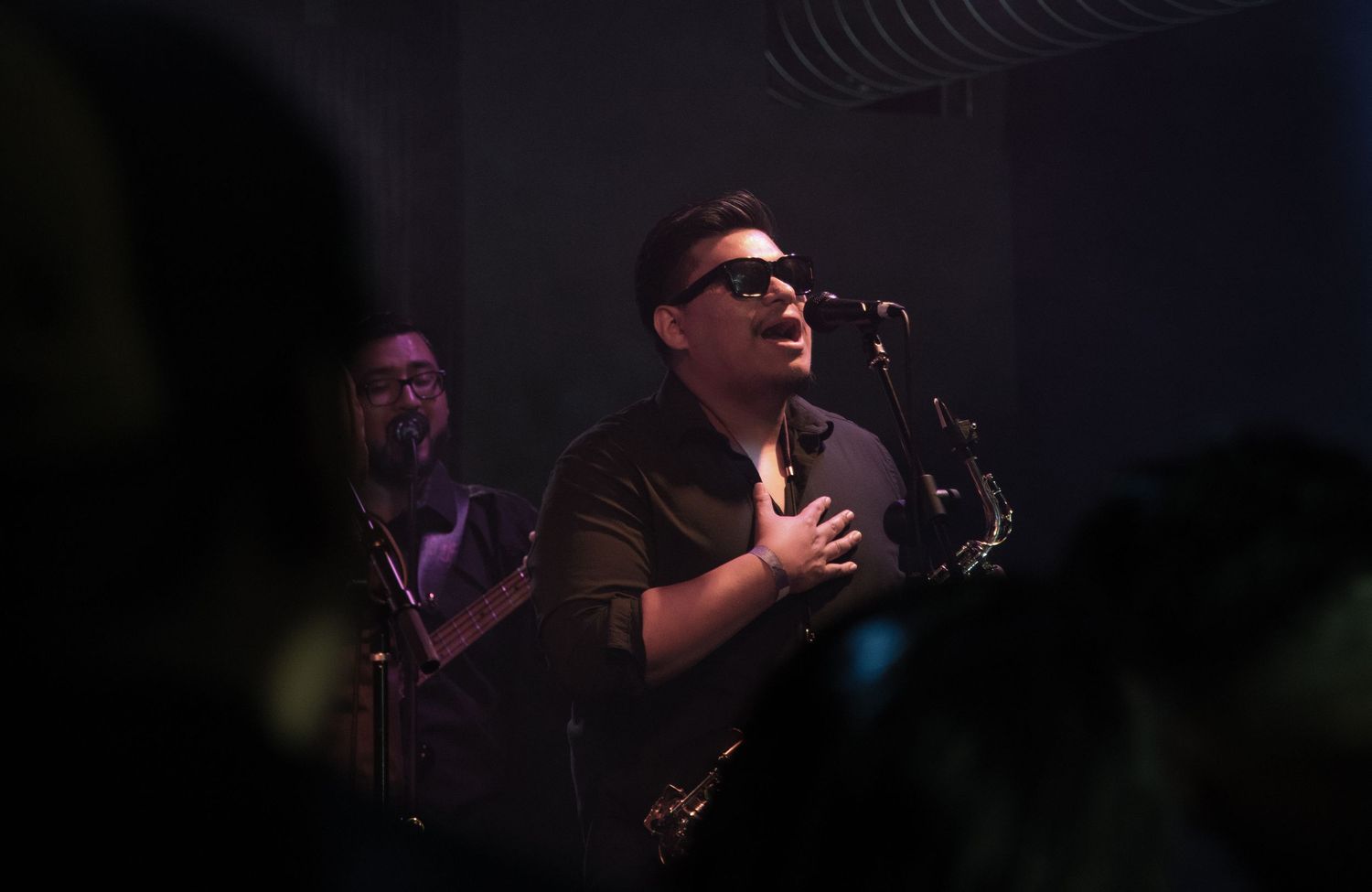 A performer sings passionately on stage during a concert with dramatic lighting and atmosphere.