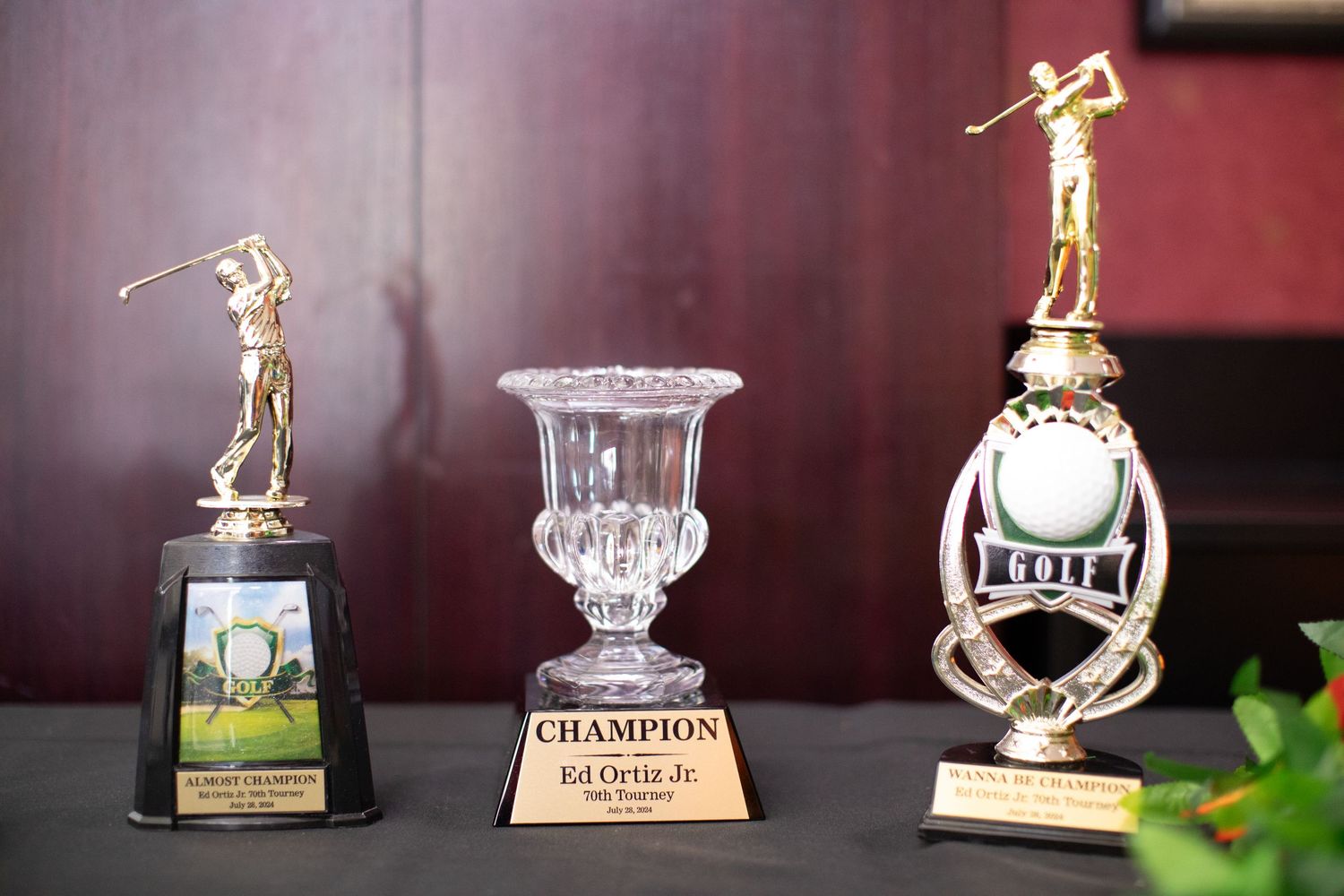 Three golf trophies displayed on shelf featuring champion cup and golfer figurines.