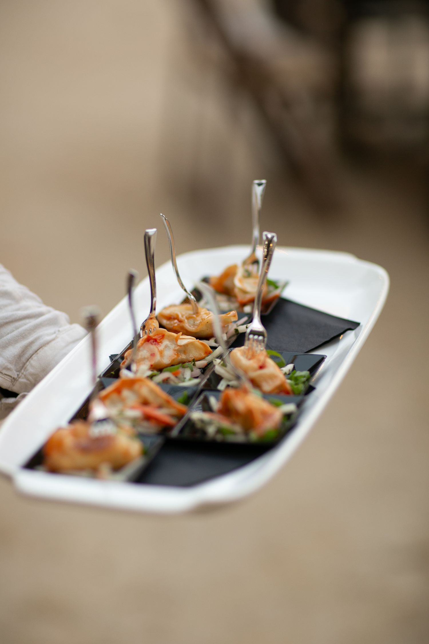 Elegant appetizers served on black slate plates with silver serving utensils.
