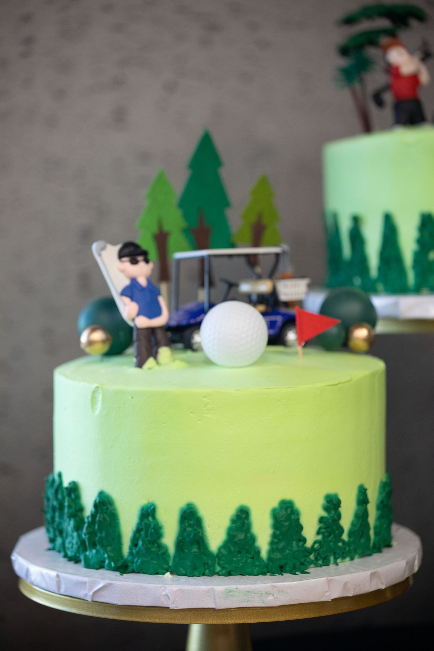 A golf-themed green cake decorated with pine trees and a miniature golfer figure on top.