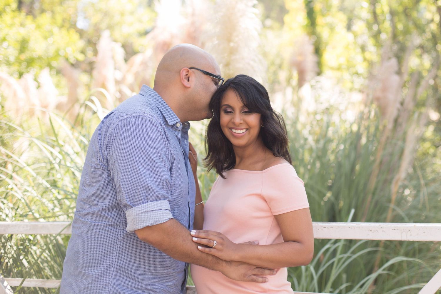 Happy couple embracing outdoors among pampas grass in a romantic moment.