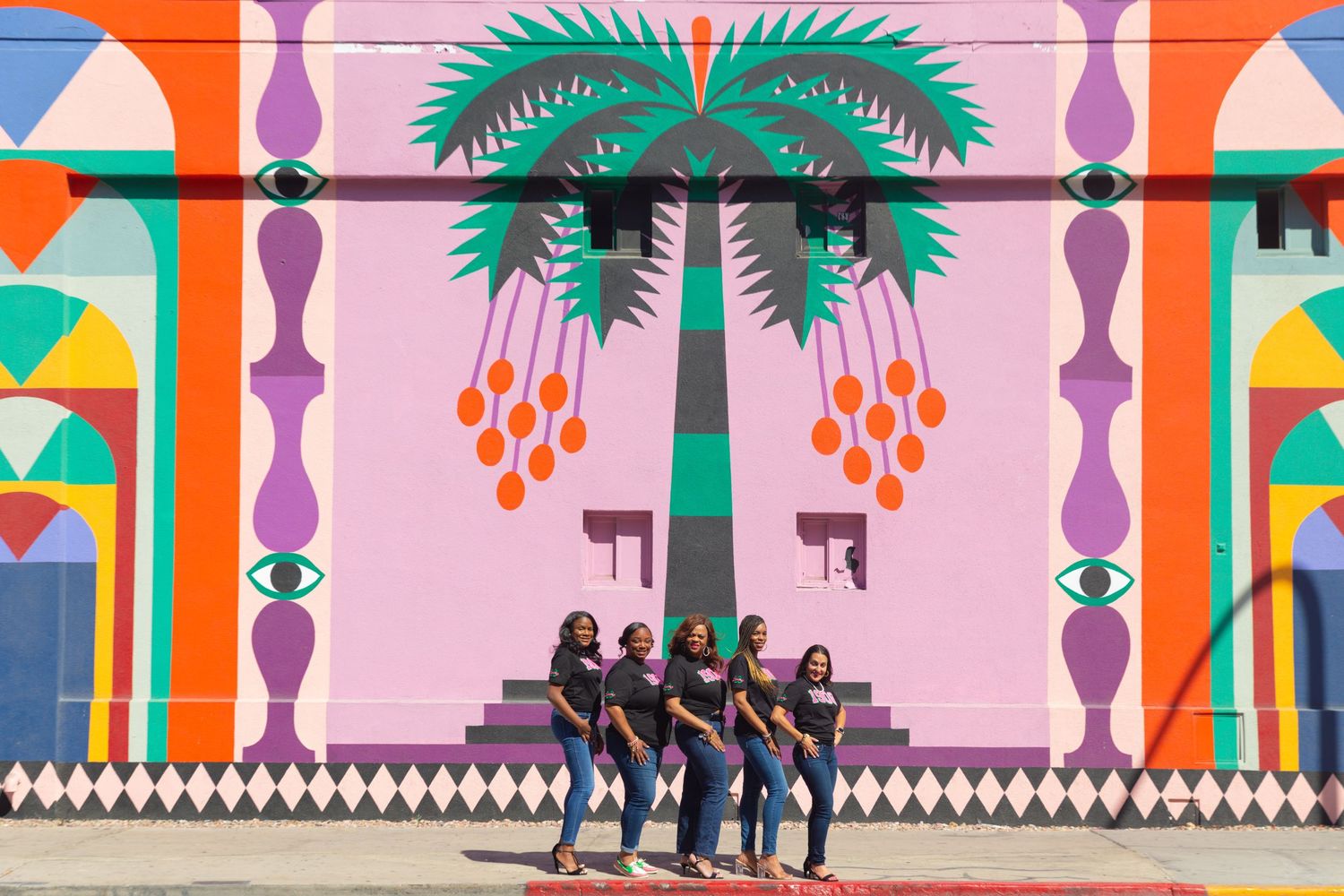 Vibrant wall mural featuring tropical palm trees and geometric patterns in pink and orange.