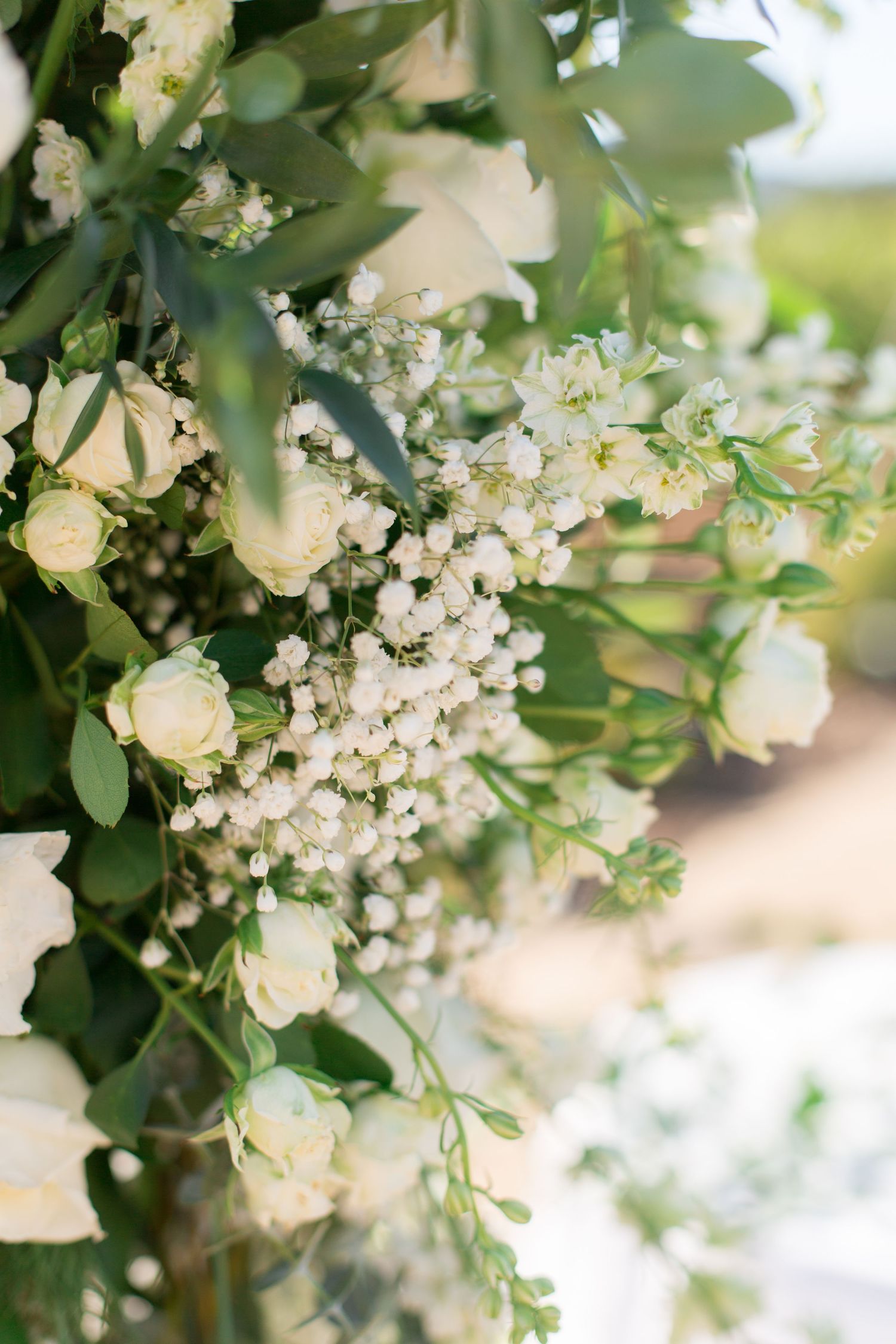 Romantic white floral arrangement with roses and baby's breath against soft natural lighting.