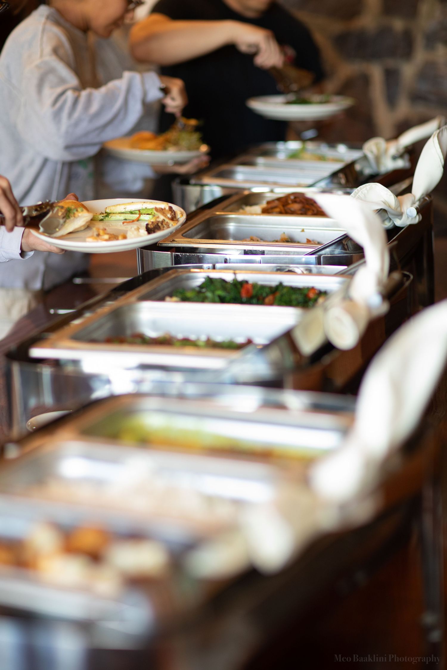 Buffet line with chafing dishes and guests serving themselves at an elegant event.