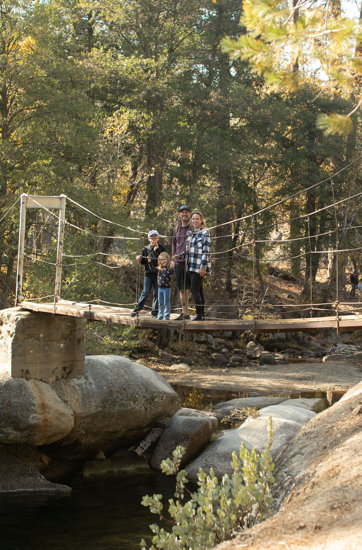Rustic wooden bridge spanning over rocky terrain in a forest setting.