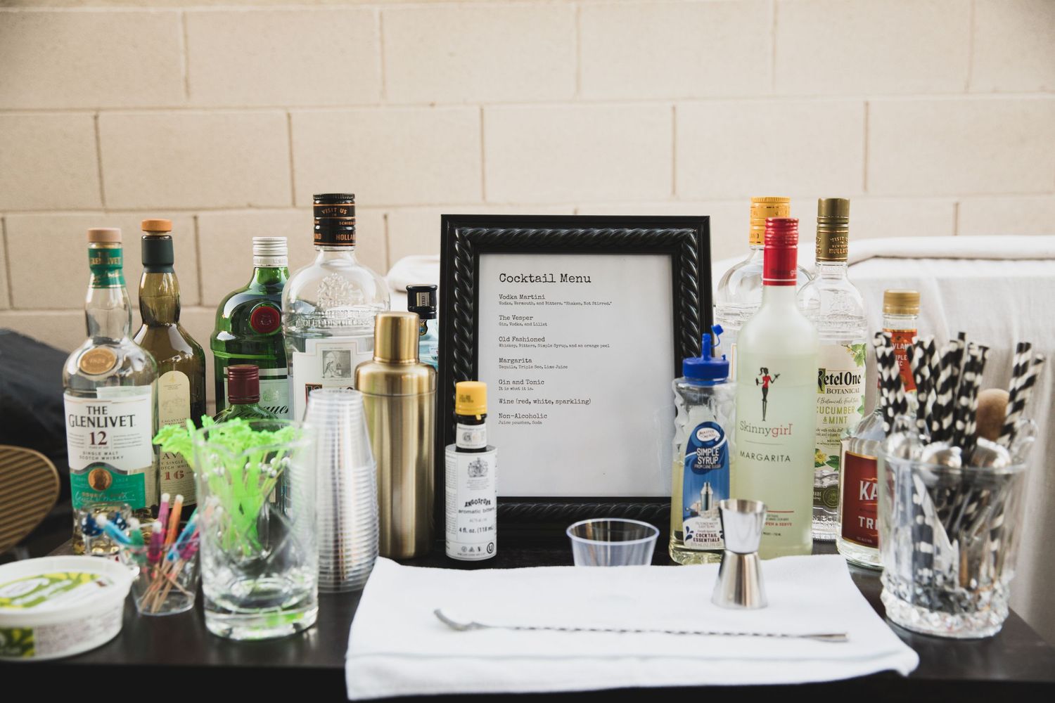 Bar setup with various liquor bottles, mixers, and cocktail supplies displayed on a black tablecloth.