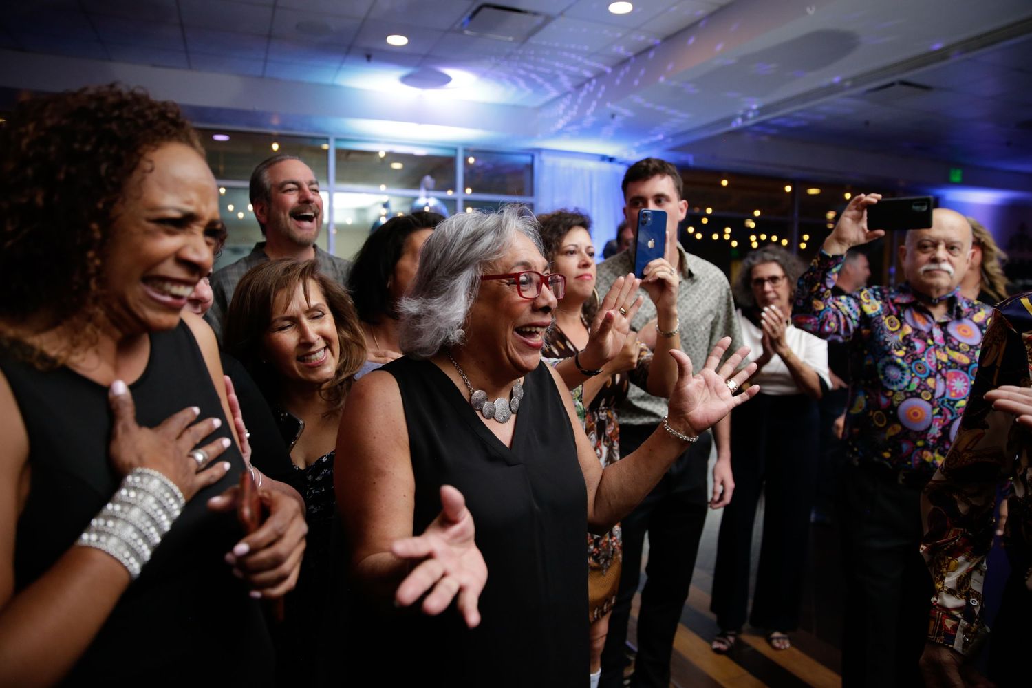 Group of party guests singing and dancing enthusiastically at celebration event.
