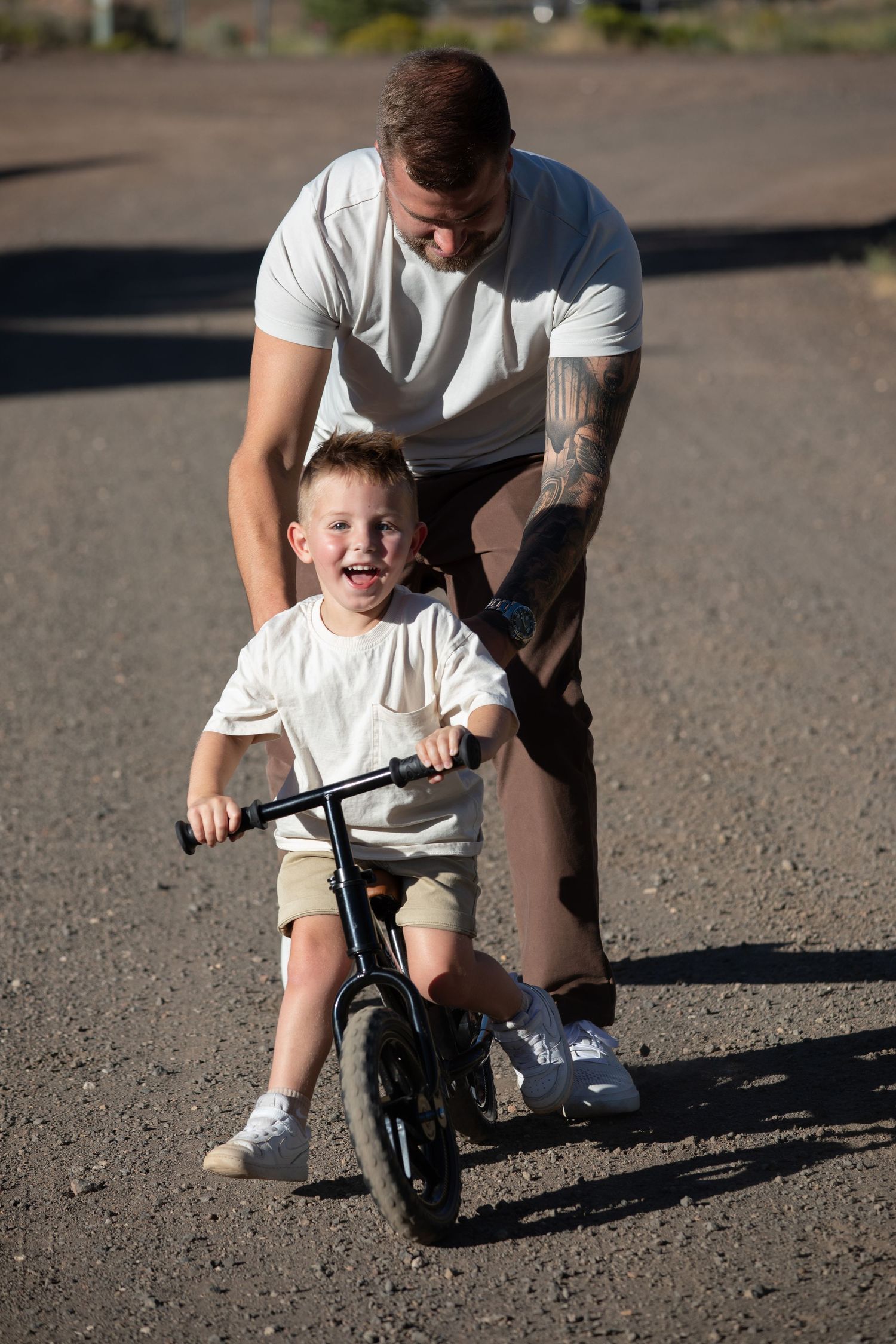 A heartwarming moment of learning to ride a bike with family support on a sunny day.