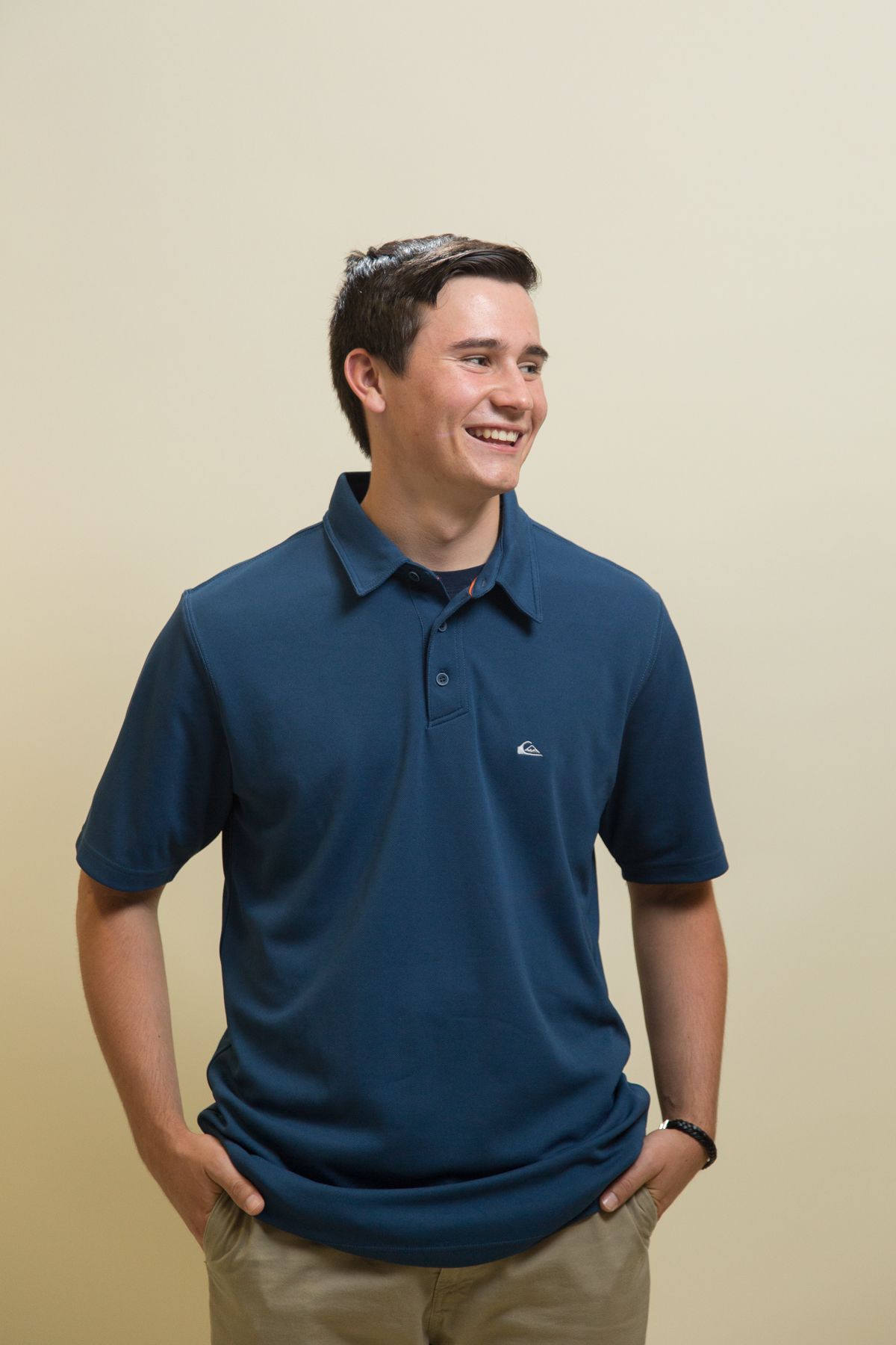 Portrait of person in navy polo shirt against beige background.