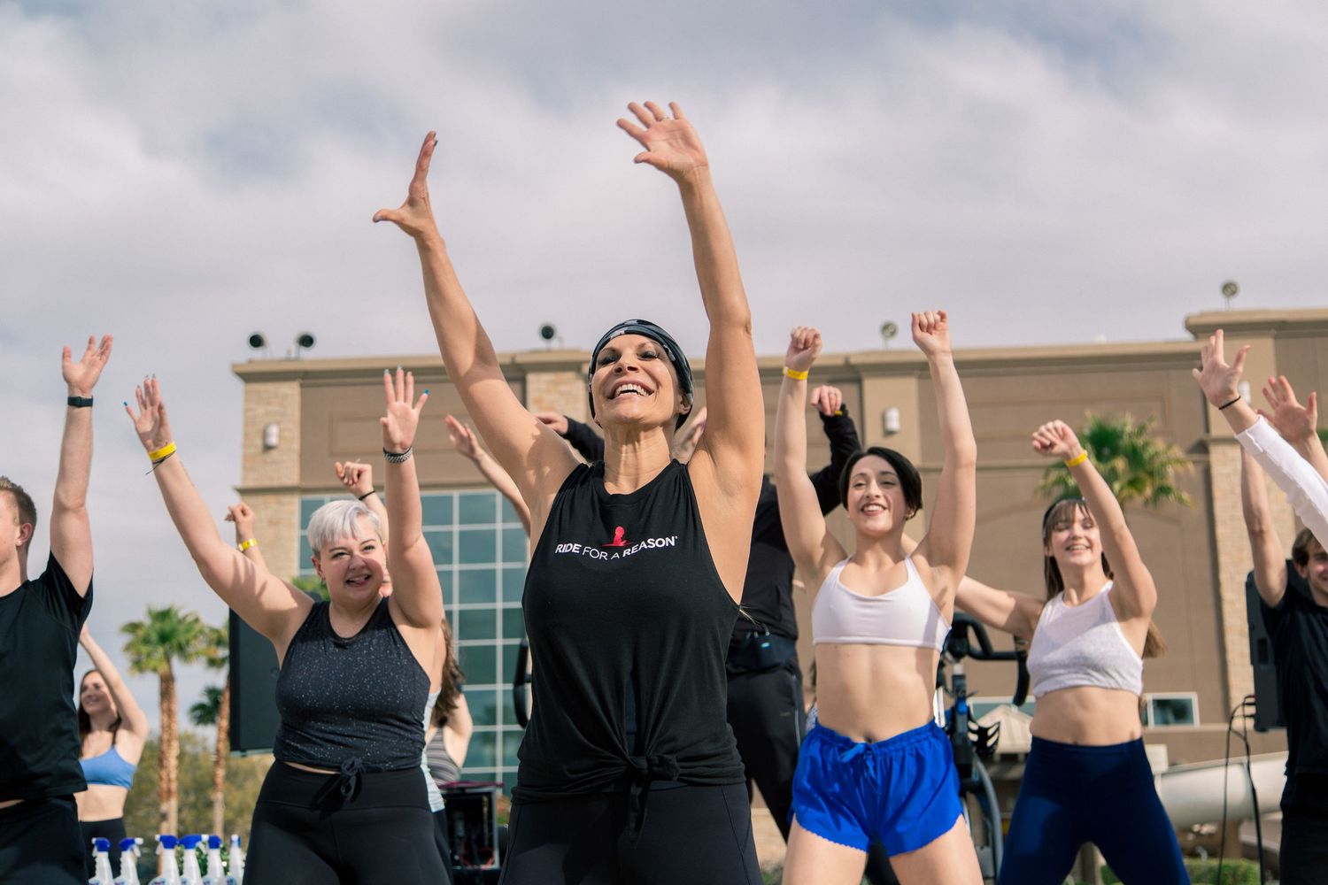 Group of people exercising outdoors with their arms raised in celebration.