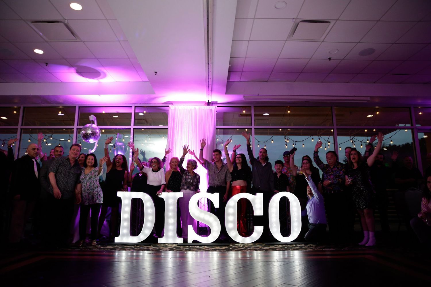 Purple disco lights illuminate a dark nightclub dance floor.