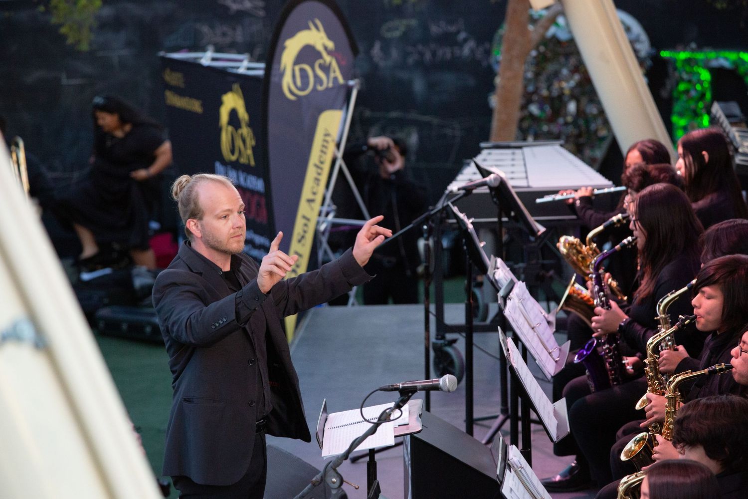 Jazz ensemble performs during a nighttime concert with brass and woodwind instruments on stage.