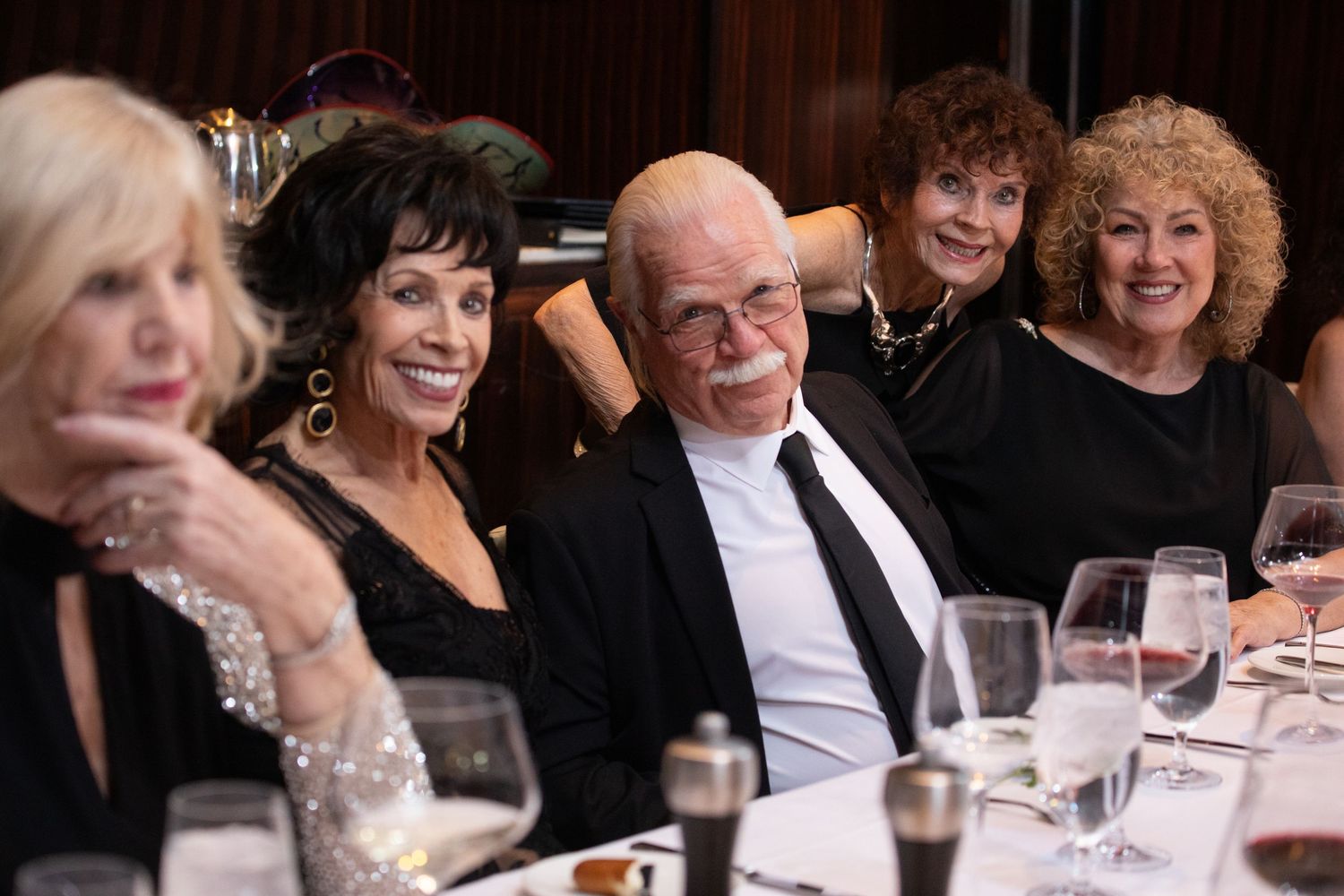 Guests enjoying a formal dinner celebration at elegantly set tables.