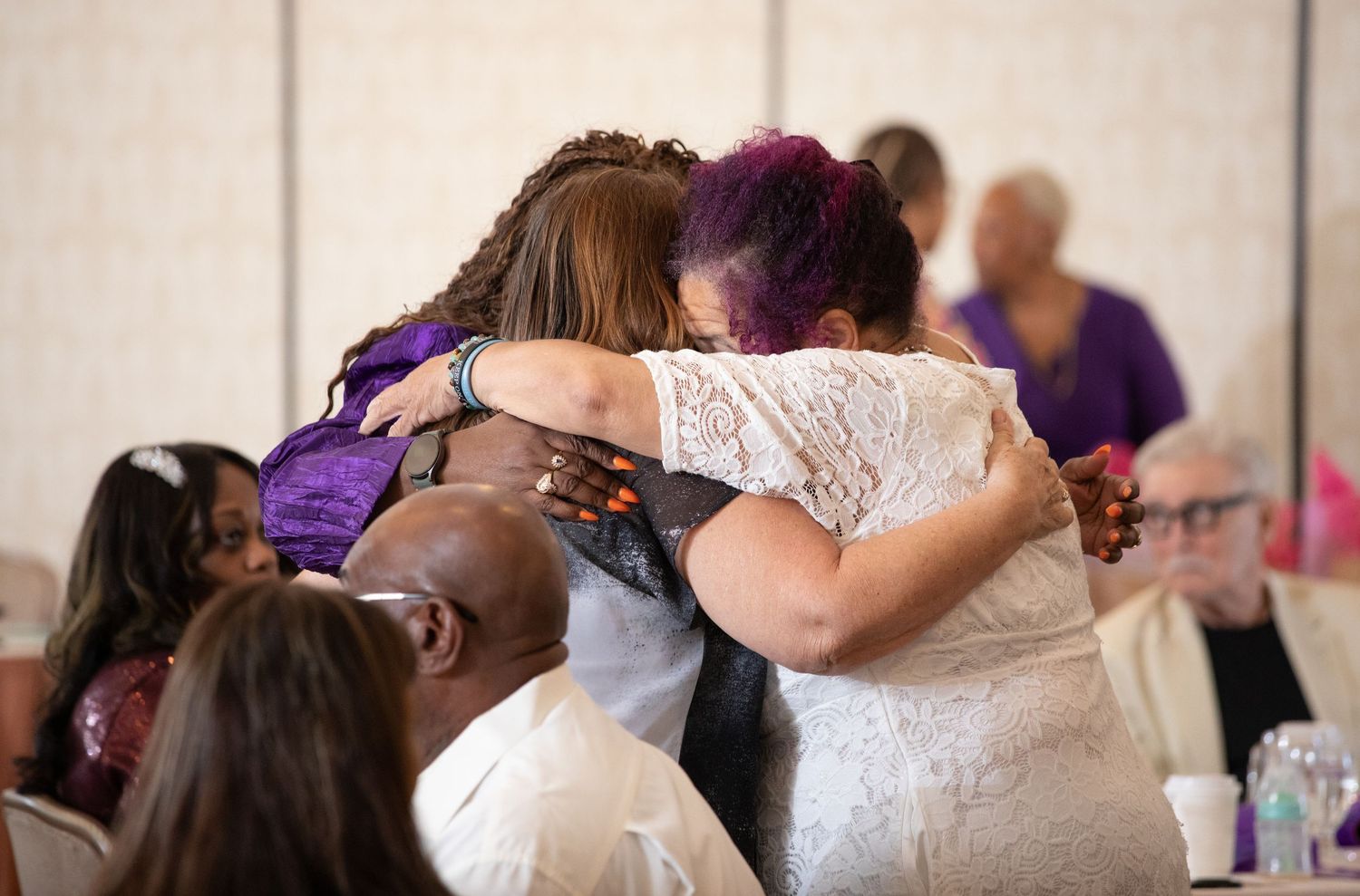 Emotional wedding reception moment with guests embracing in celebration.