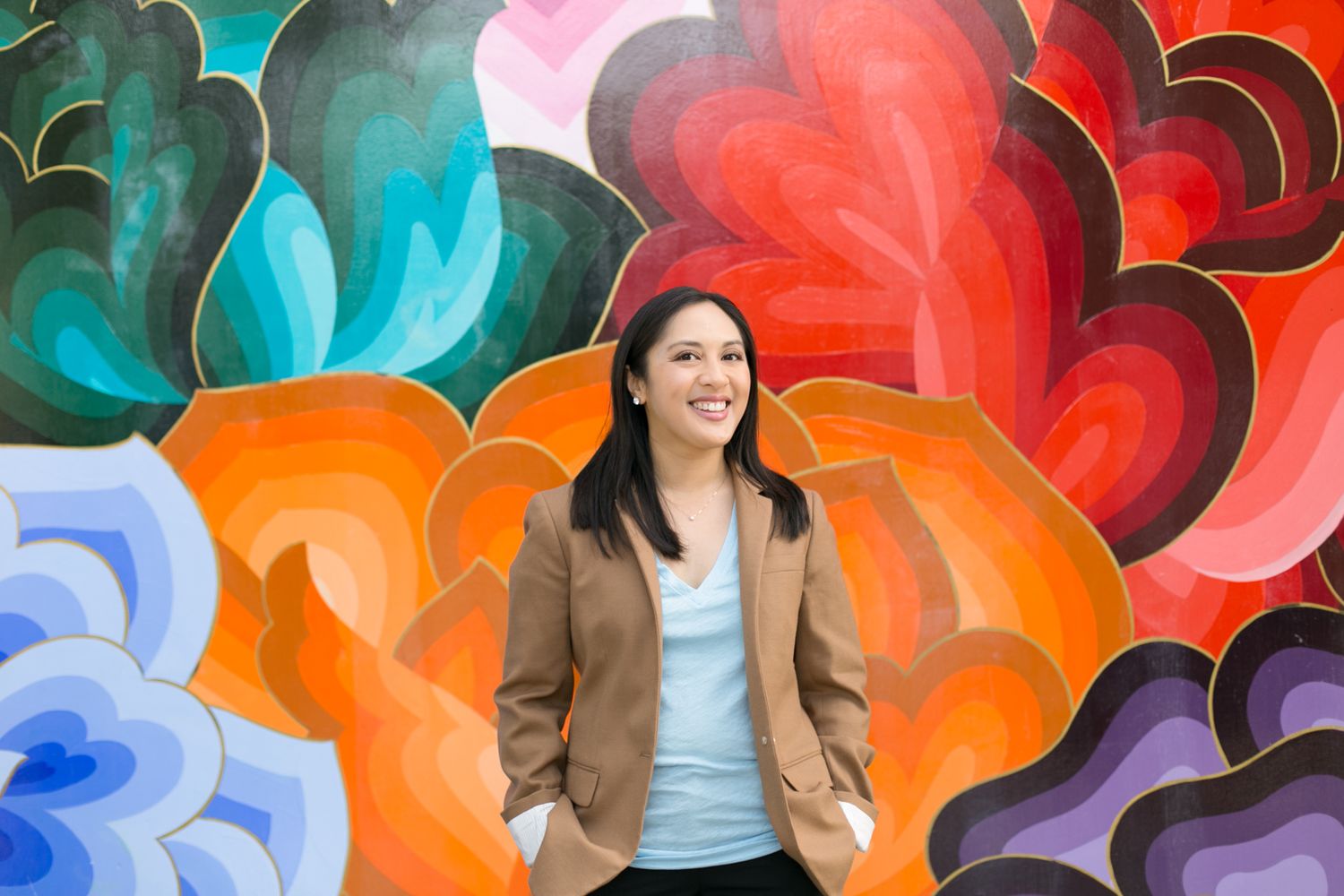 Casual business look against vibrant colorful mural with floral patterns.
