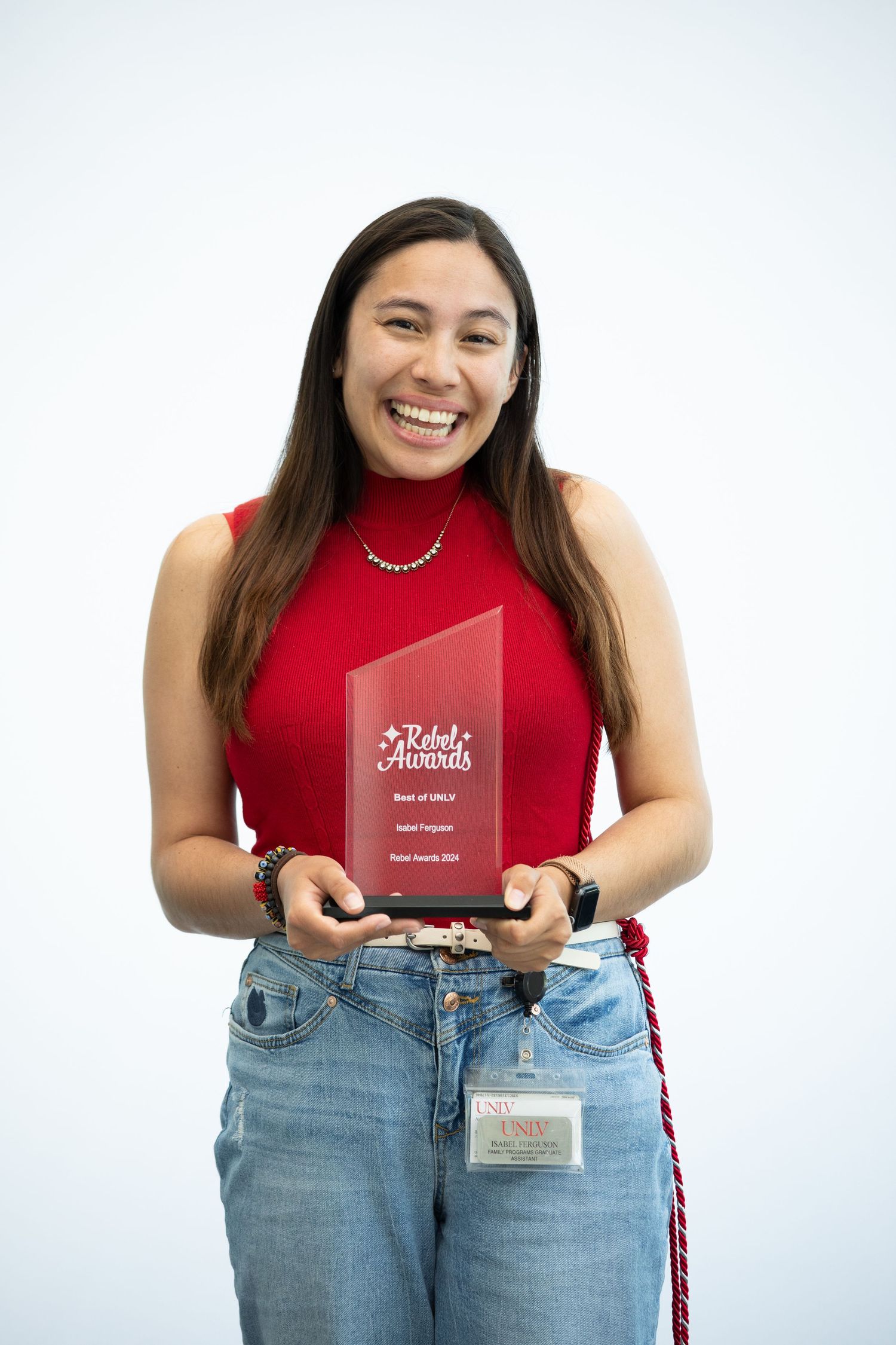 Graduate displaying academic awards and diploma holder against white background.