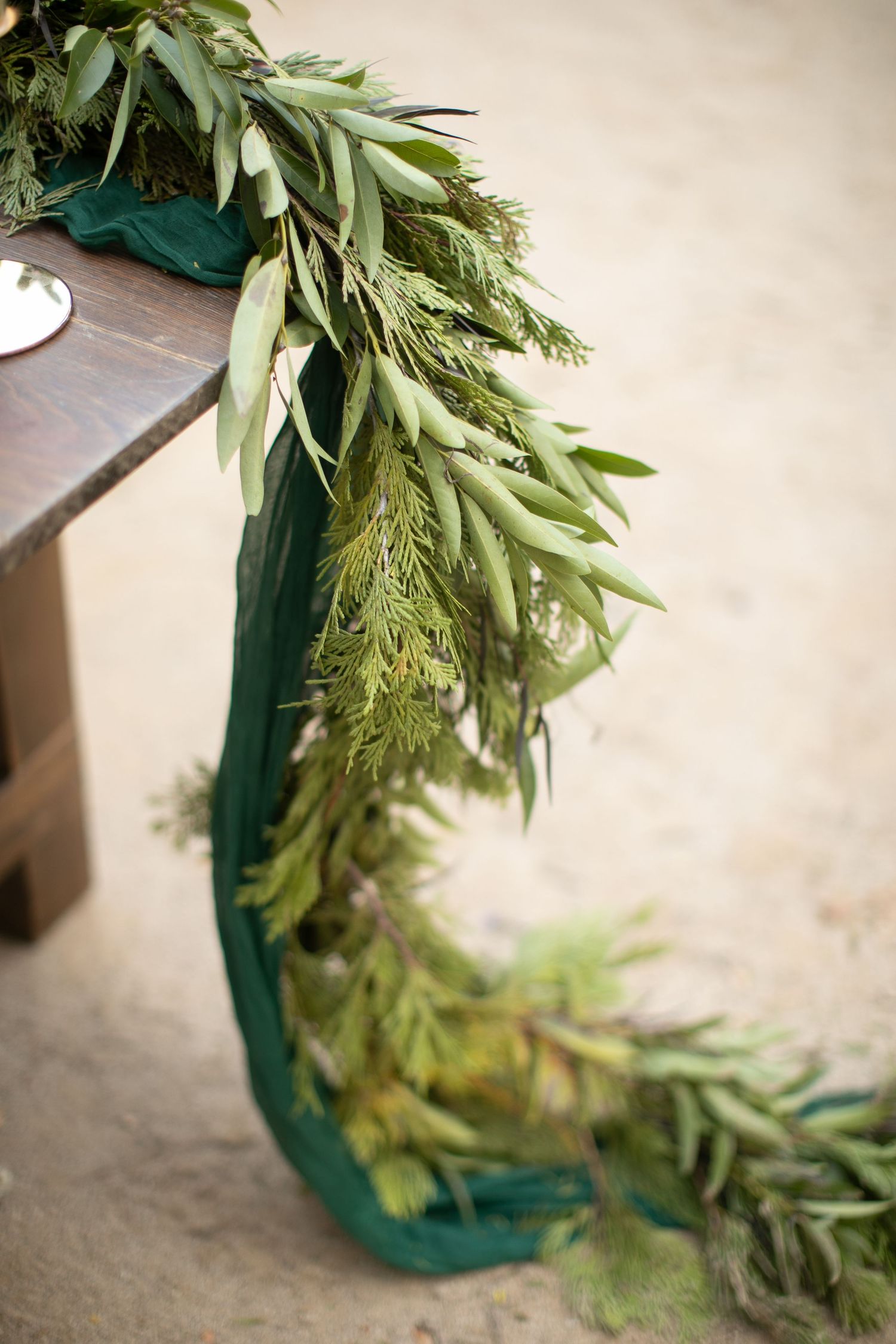 Fresh eucalyptus and greenery garland draped along a teal-colored surface for wedding decor.