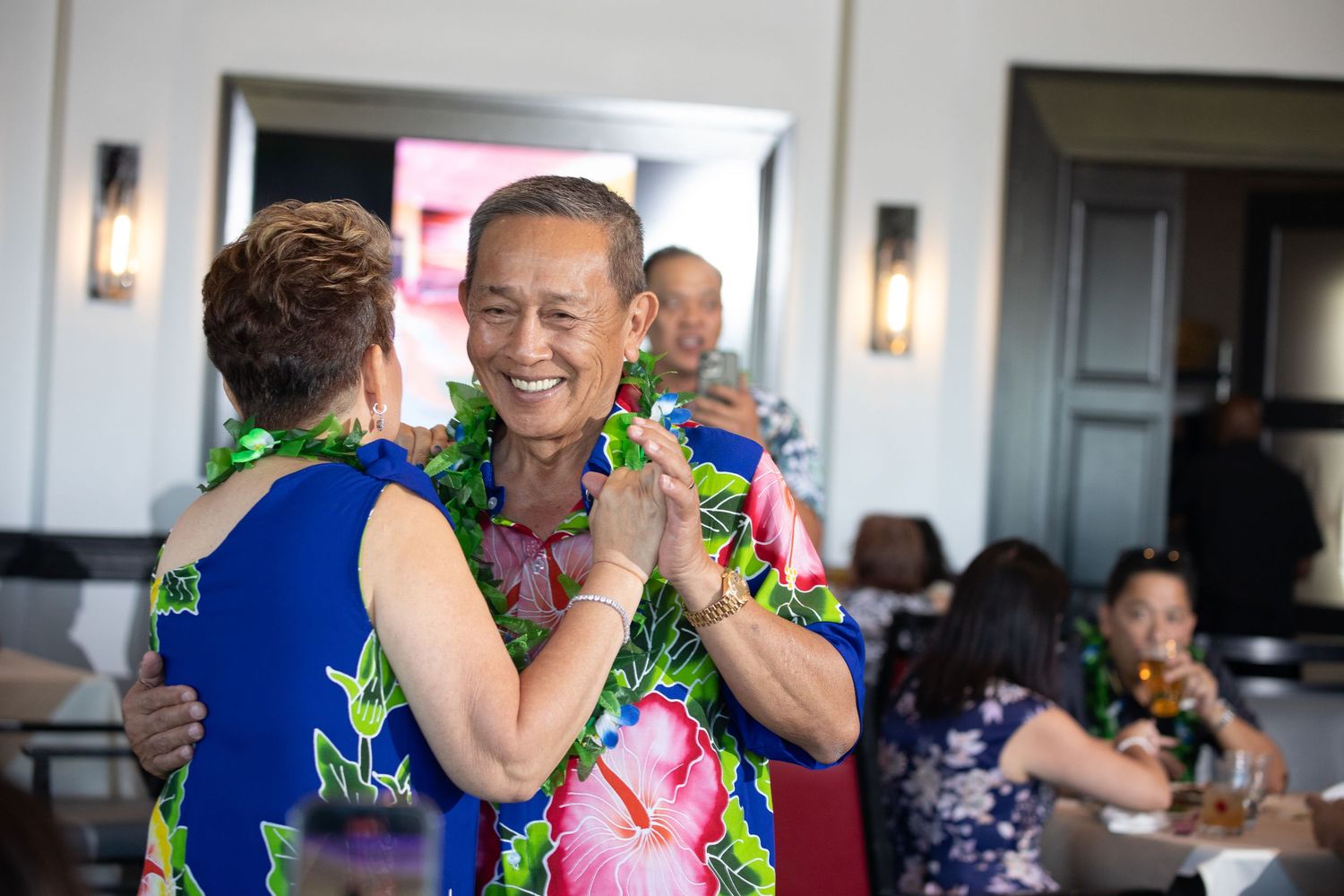 People wearing tropical floral prints share joyful moments at a celebration.