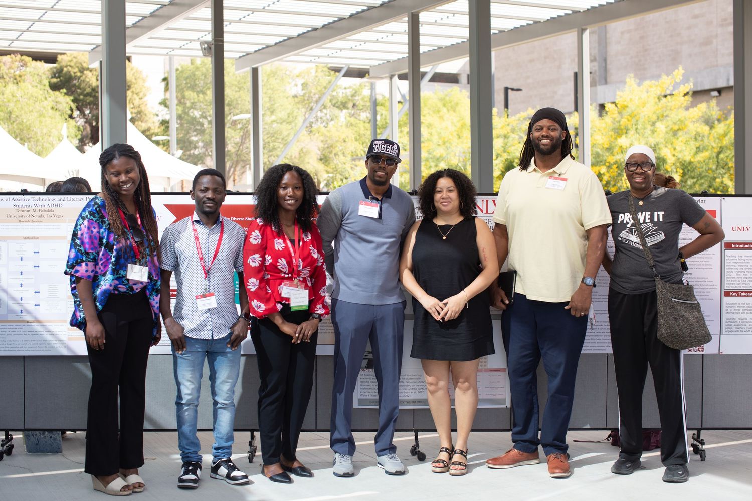 A group of diverse individuals pose together under a covered outdoor area.