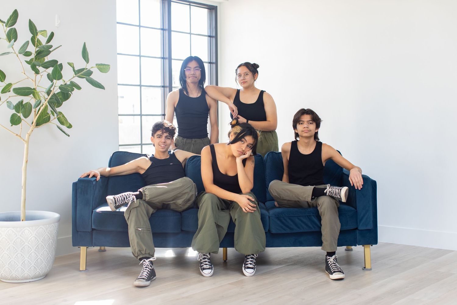 Musicians relax on blue couch in casual performance attire.