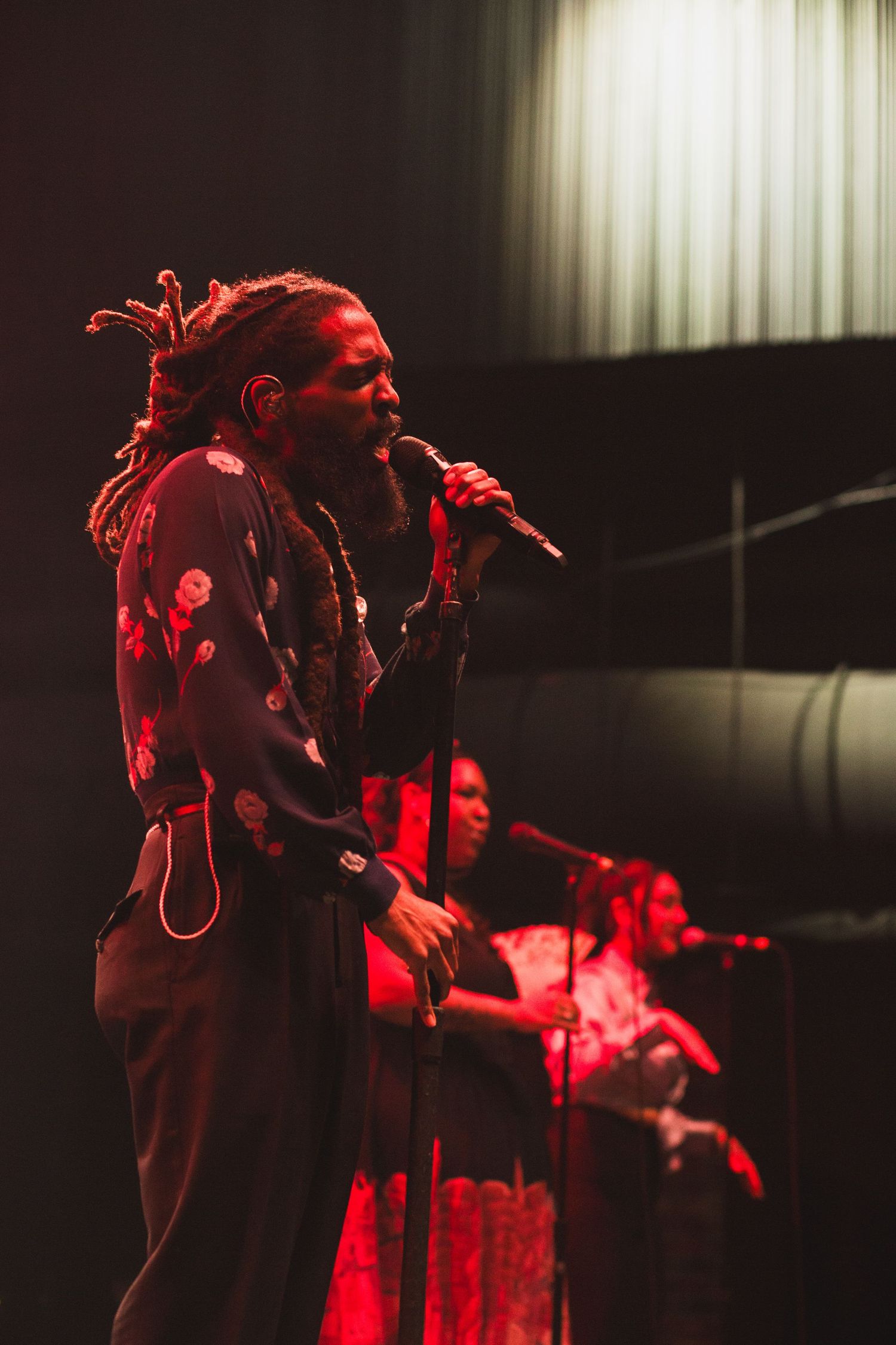 Singer performs passionately on stage under dramatic red lighting during a live concert performance.