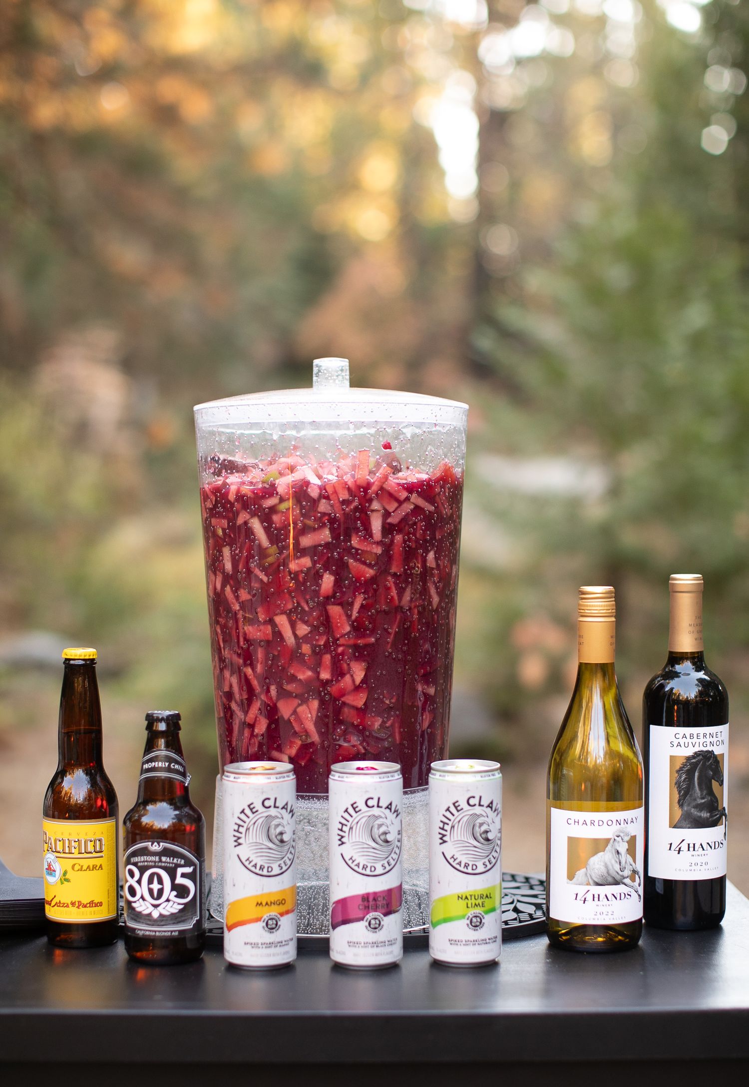 Various drink bottles and cocktail mixers lined up with red sangria in large glasses.