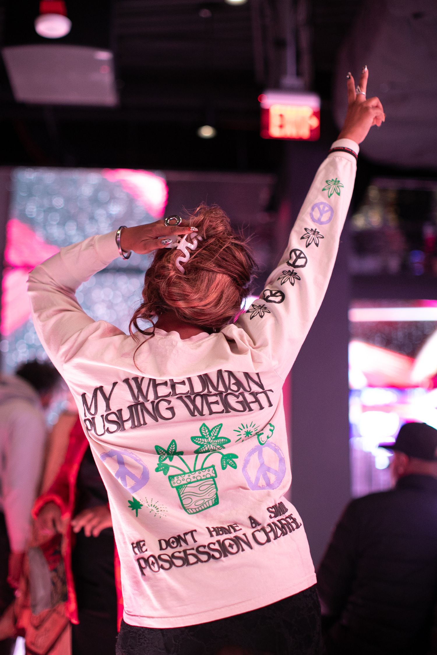 Person wearing a decorated white jacket performing on stage under pink lighting.