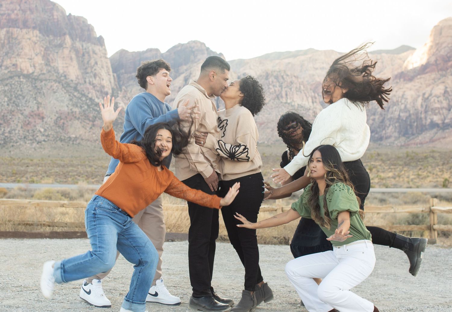 Group of friends joyfully jumping and posing together against a scenic mountain backdrop in Red Rock Canyon.
