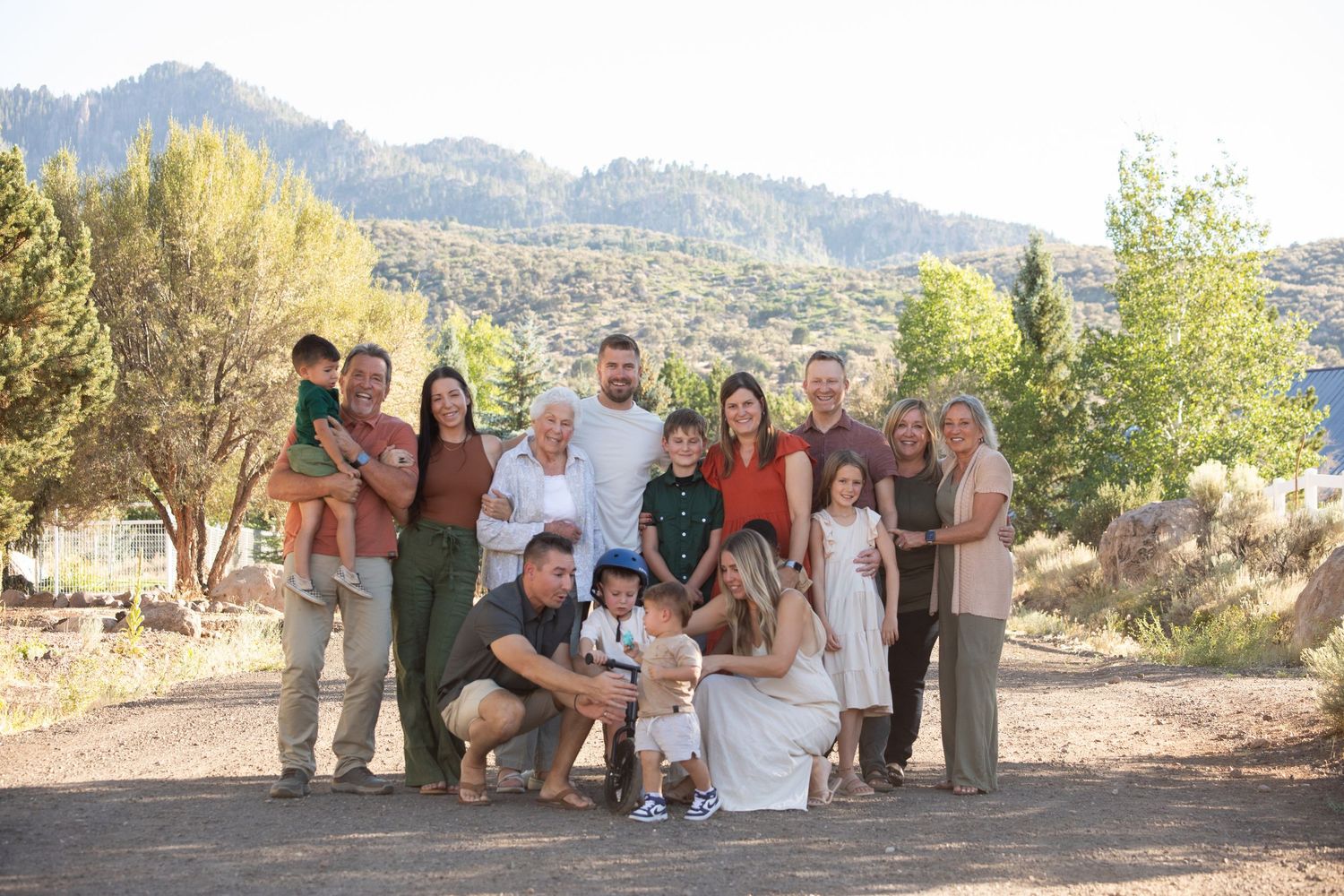 Large family group photo outdoors with mountains in the background.