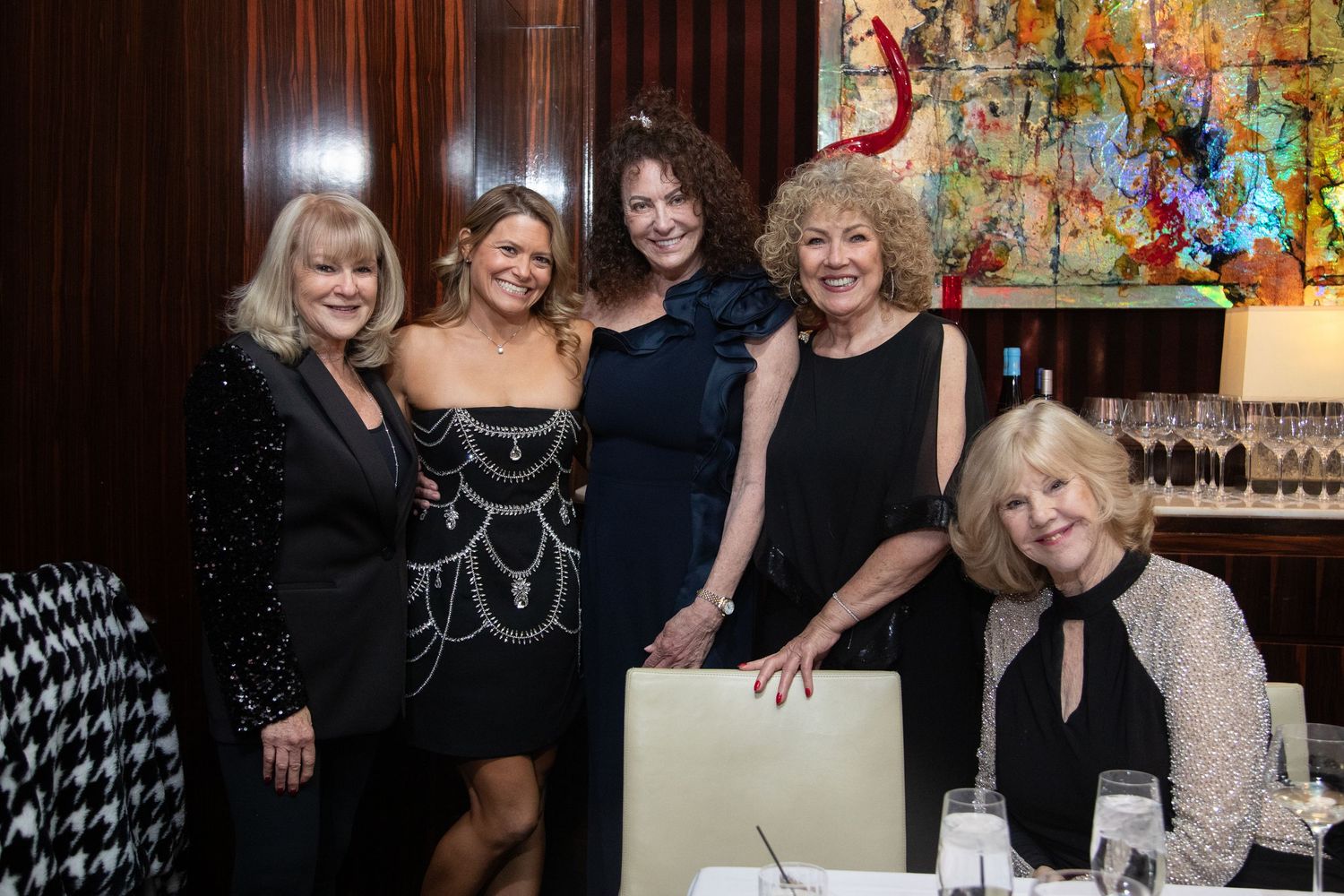 Group photo of guests at a formal celebration with abstract art decor.