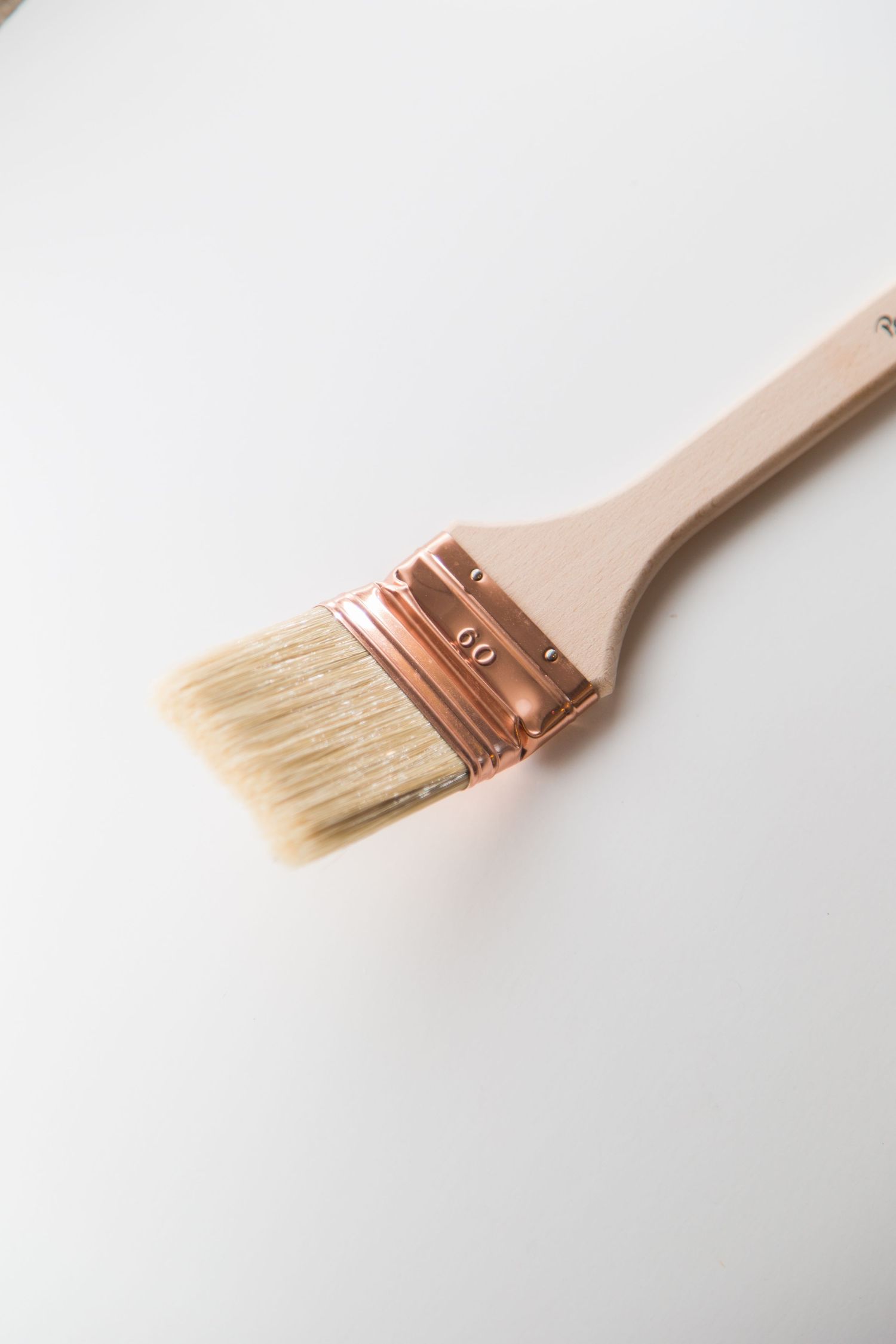 Paint brush with wooden handle and copper ferrule showing soft natural bristles.
