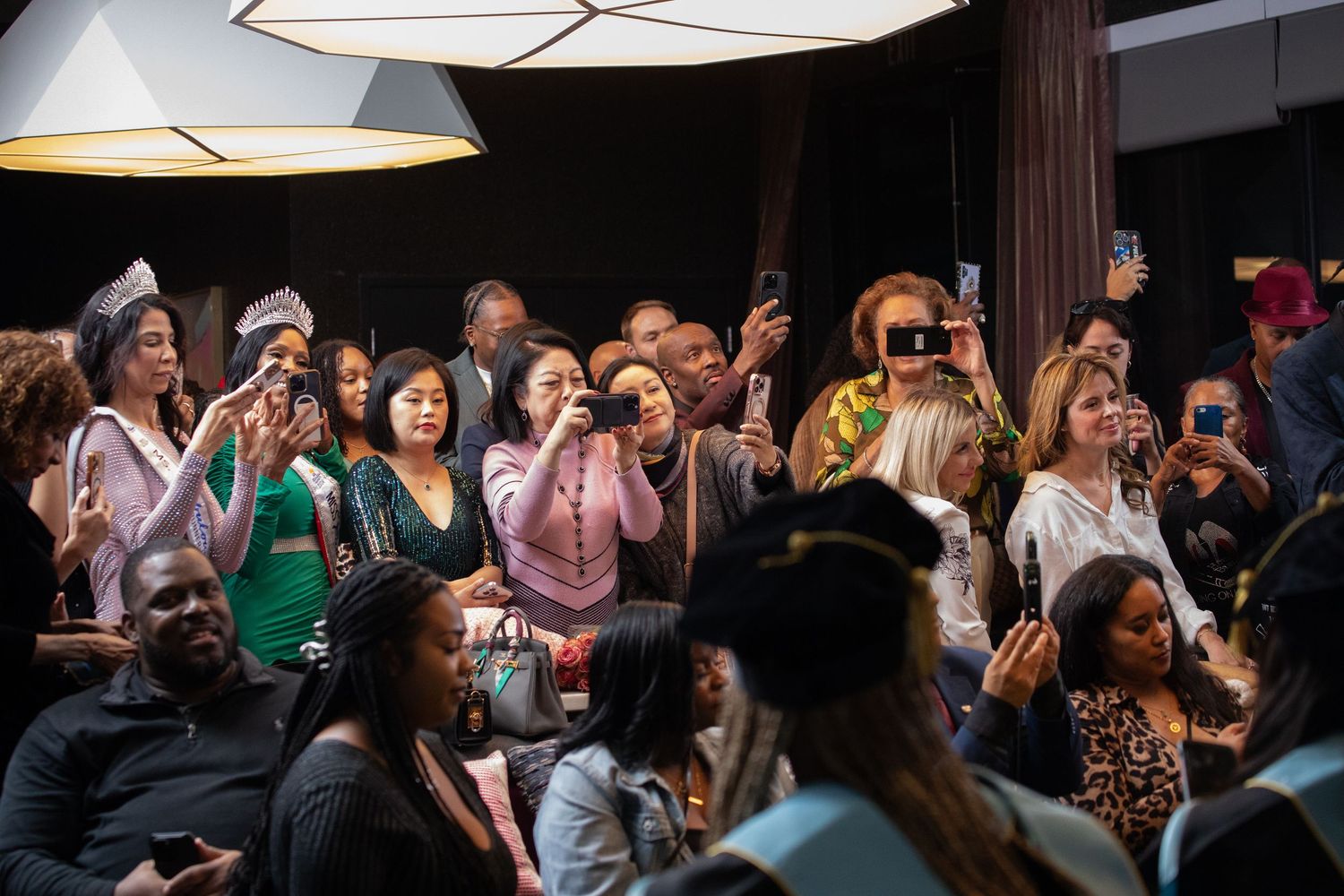 An enthusiastic crowd reacts and takes photos during an exciting event moment.