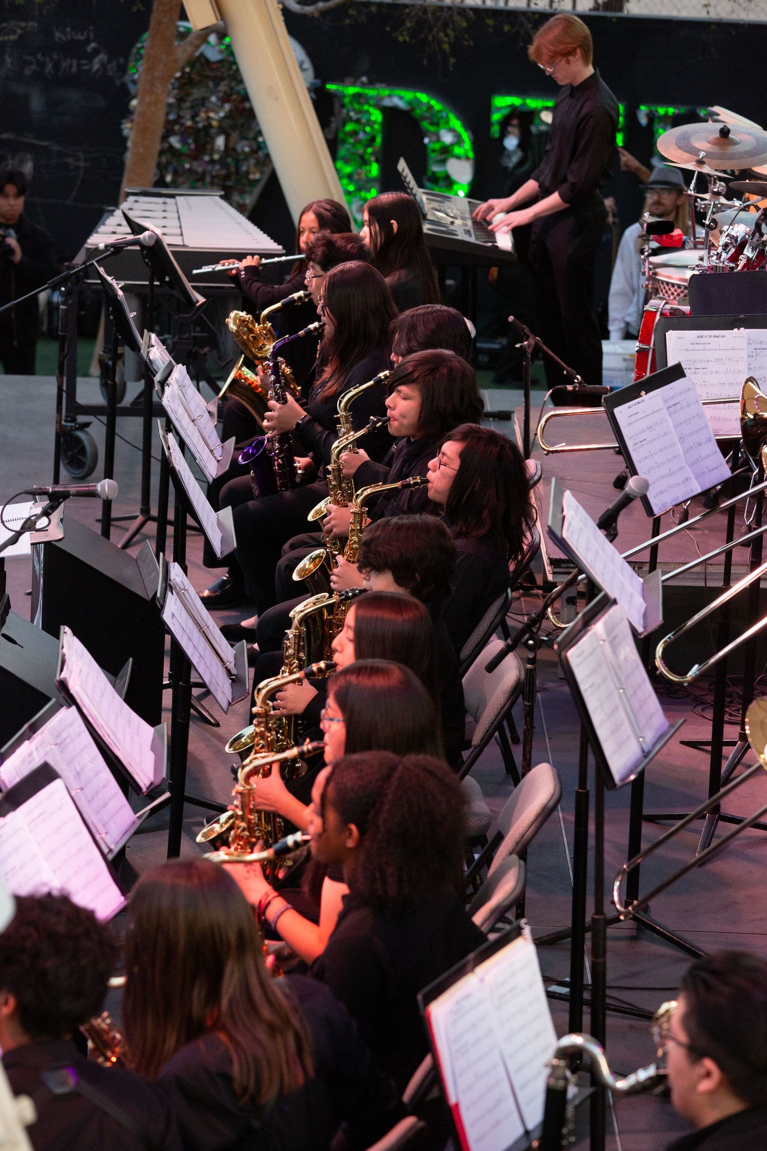 Saxophone section of jazz ensemble performs with sheet music during concert.