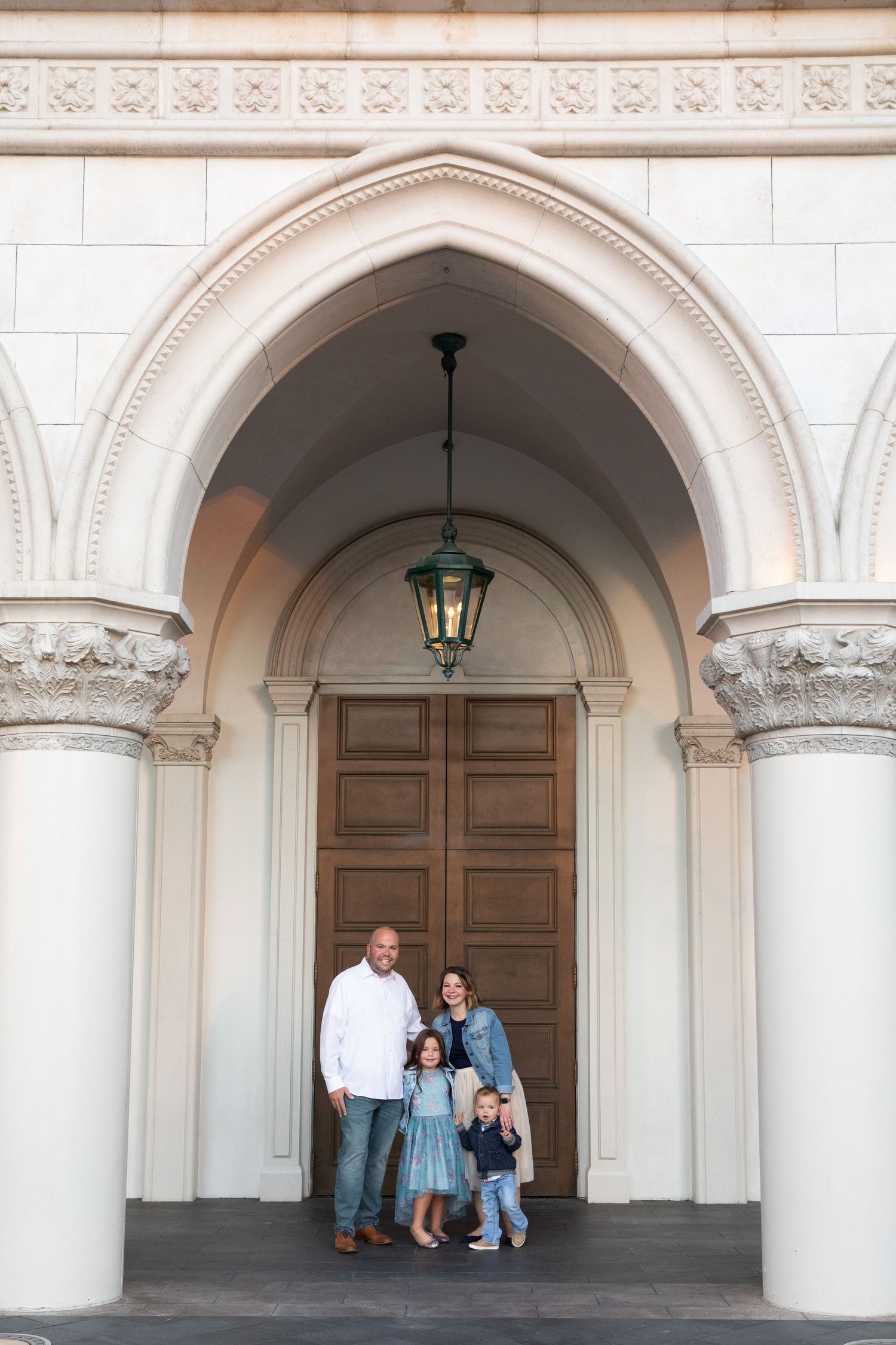 Family stands together under grand arched entrance with ornate columns.