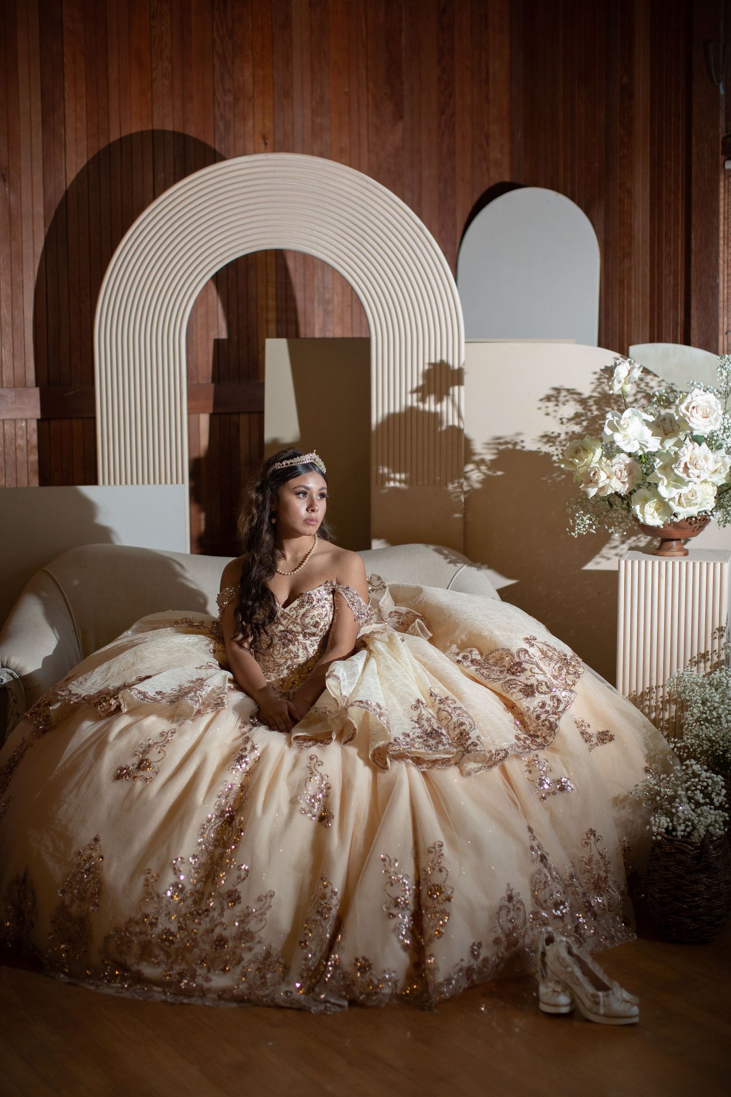 A quinceañera dress portrait against modern arch backdrop with floral arrangements.