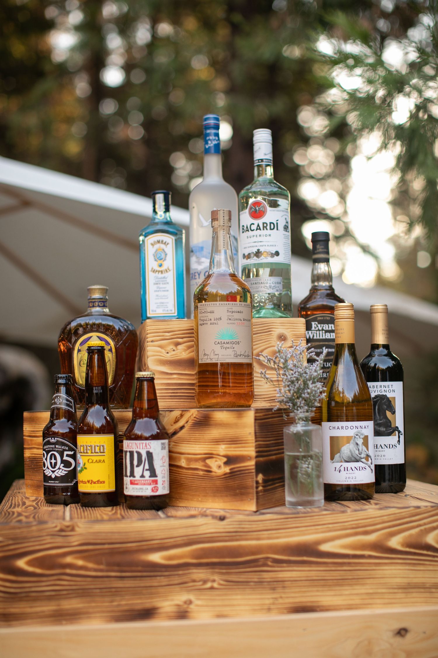 Various liquor bottles and craft beers arranged on wooden display steps.