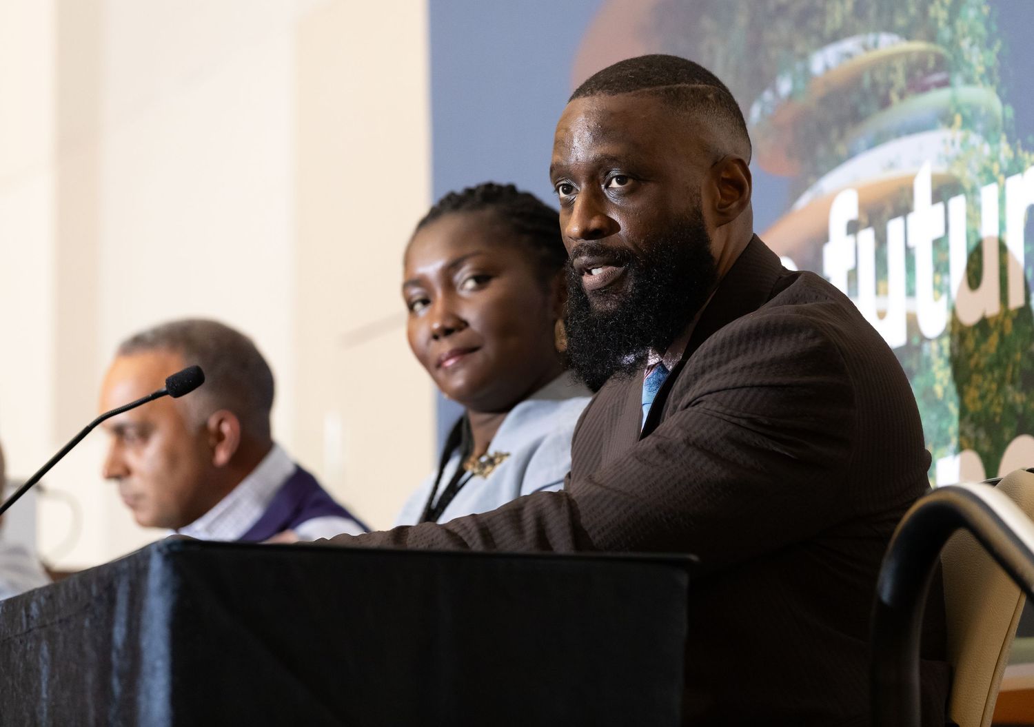 Panel speakers at podium during professional conference presentation.