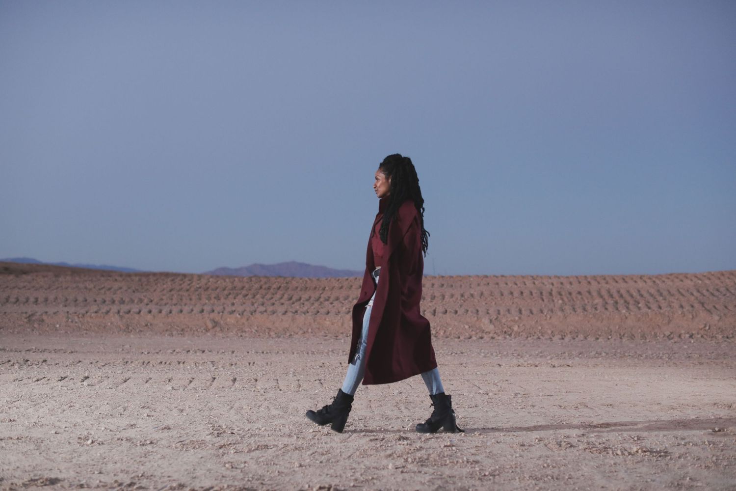 Panoramic view of a vast desert landscape with distant figures on the horizon.