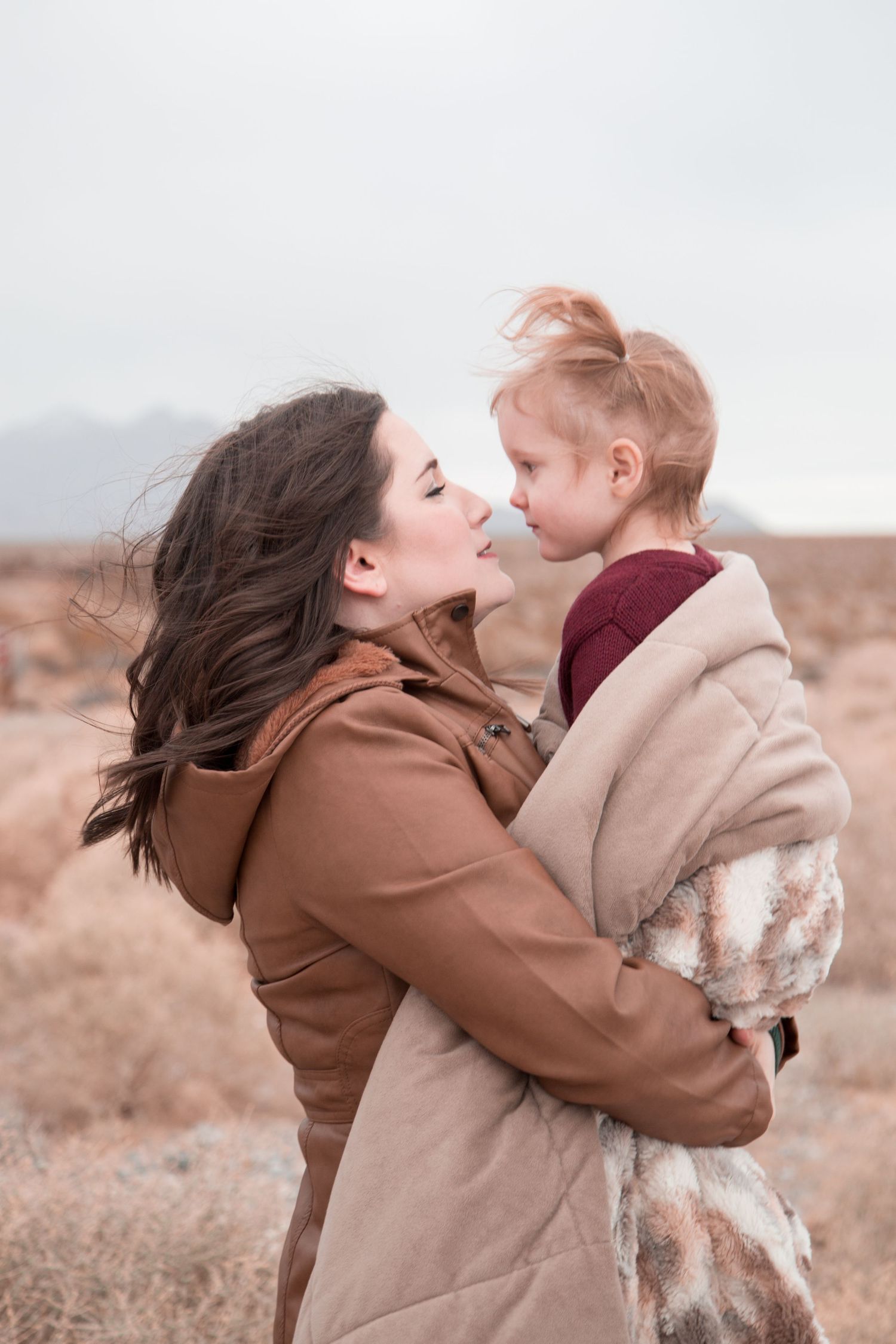 A tender moment between mother and child outdoors in warm winter clothing.