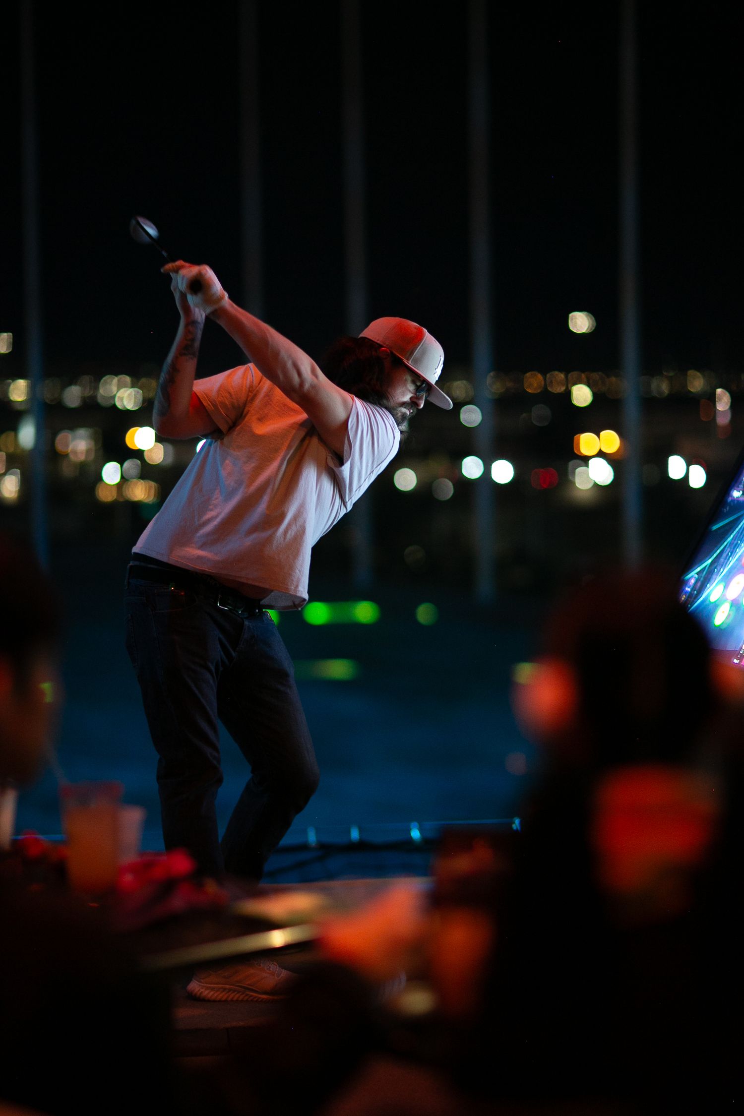 Silhouettes of people dancing in a dark venue with city lights in the background.