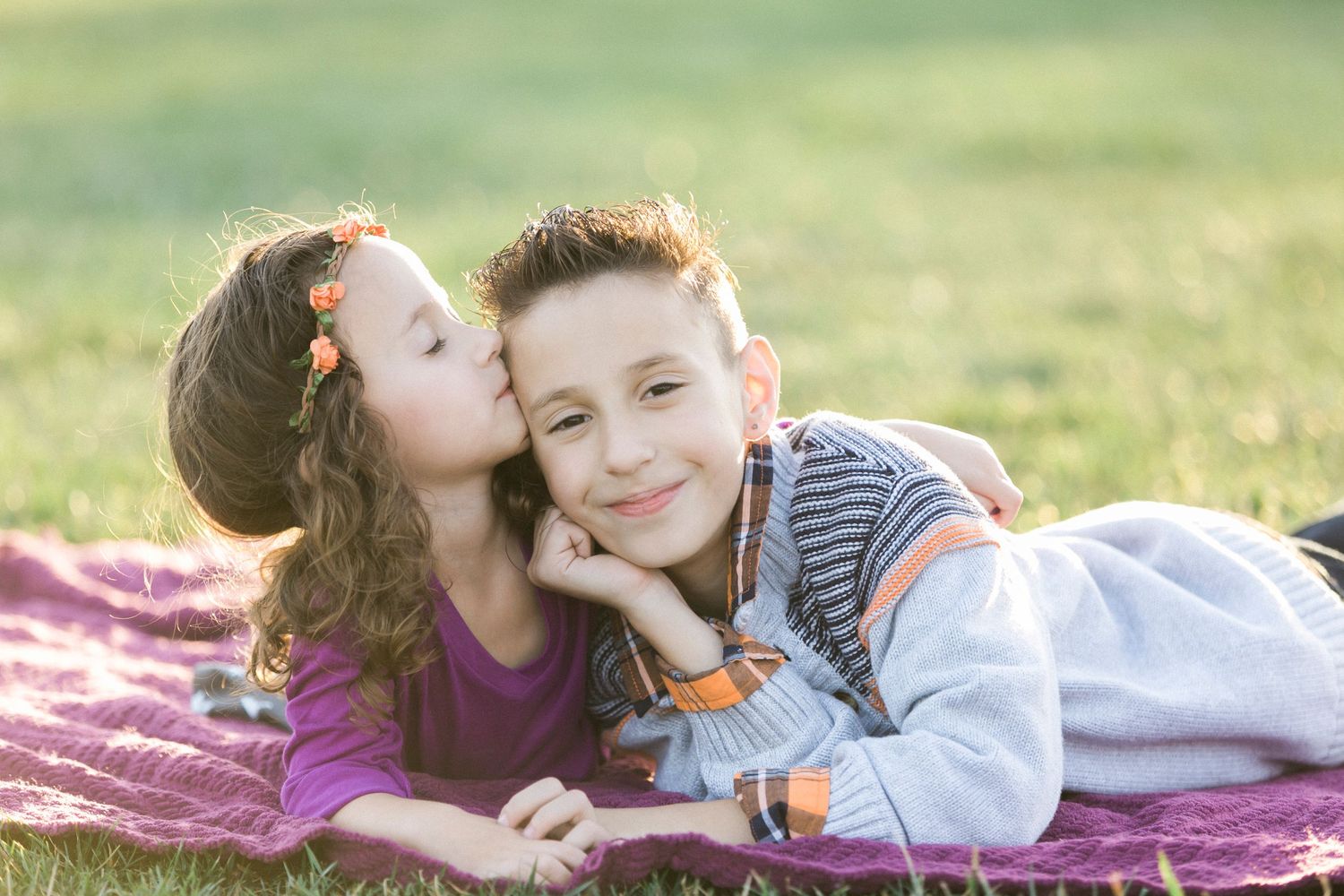 Children playing and laughing together on a blanket in golden sunlight.