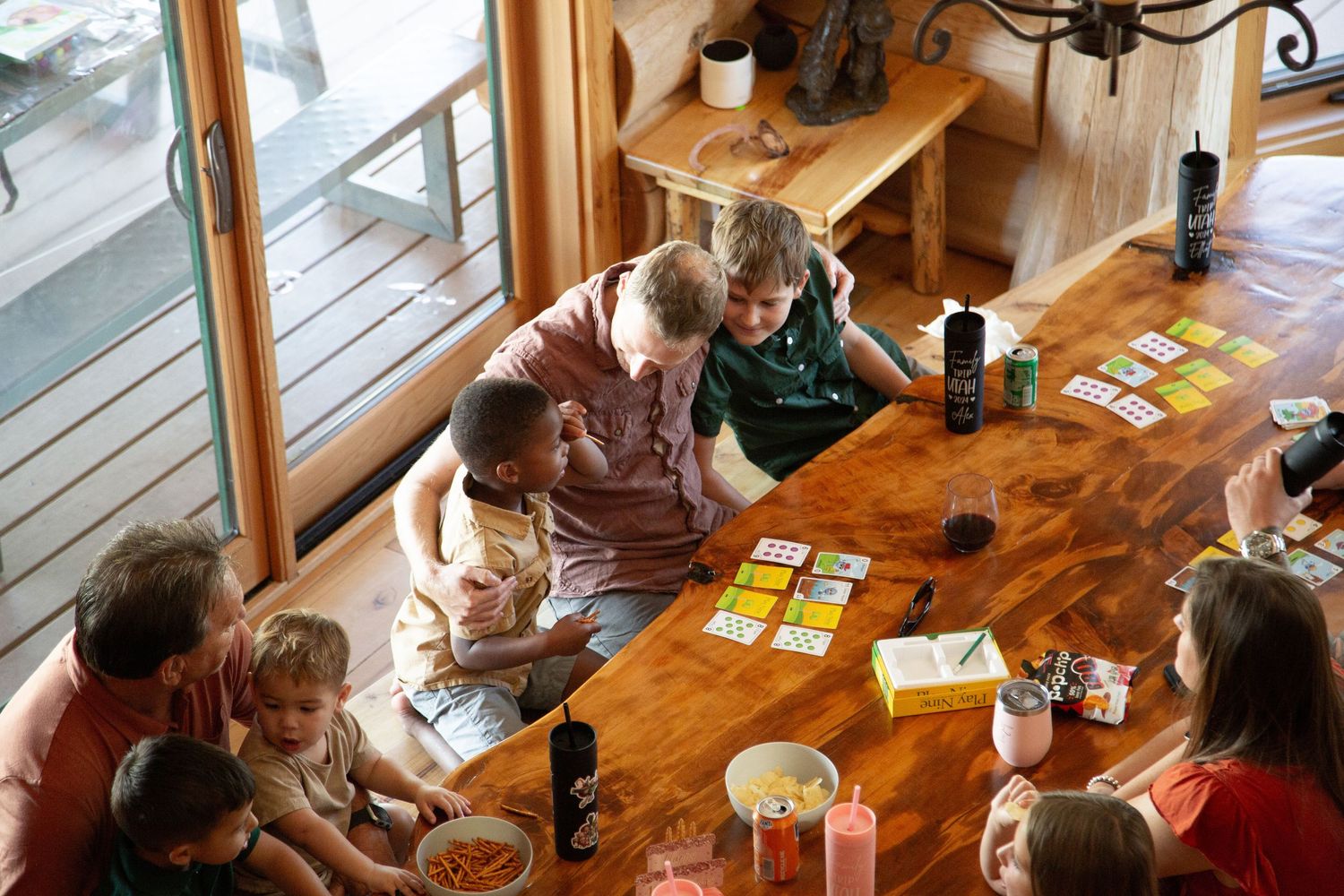 Family gathering around a wooden table playing card games together.
