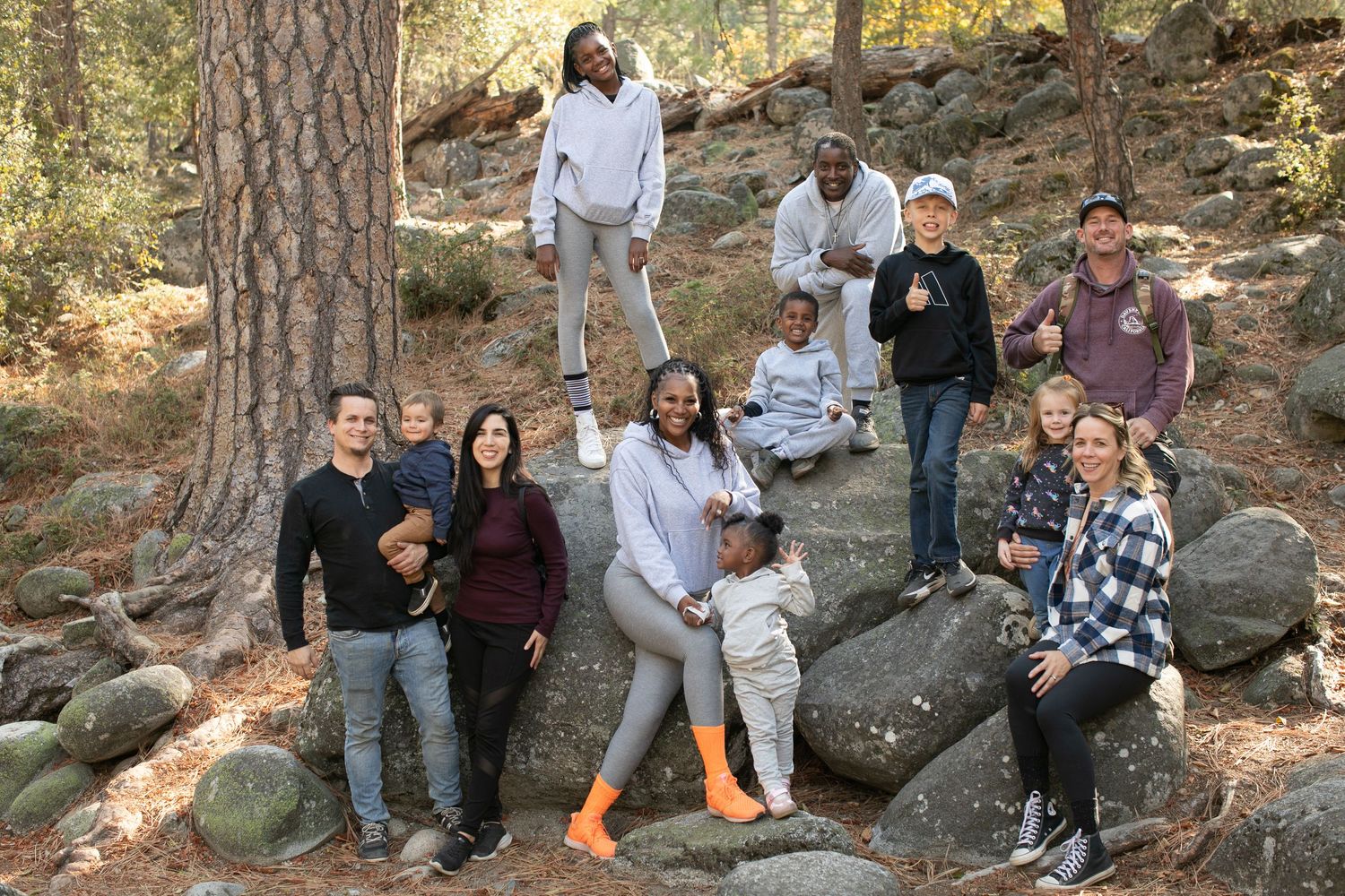 People sitting casually on large boulders in a forest setting.