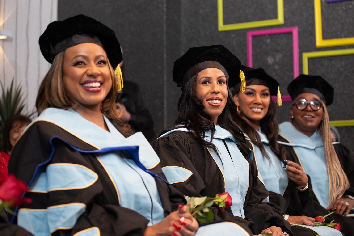 Graduates in black caps and gowns celebrate during a graduation ceremony.